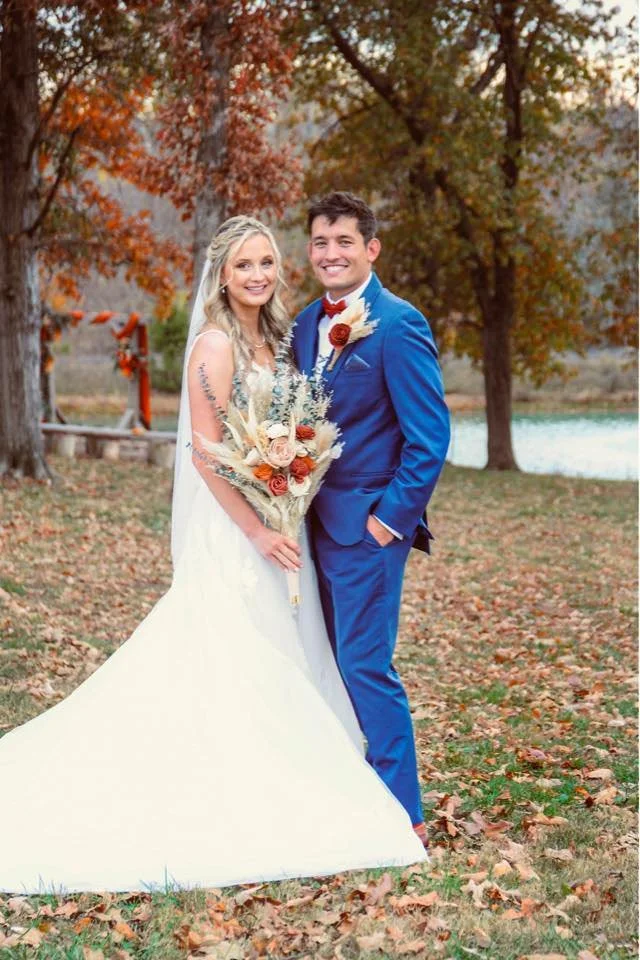 Fall wedding at Berkshire Ridge near St. Louis: A bride and groom smiling outdoors with autumn trees and a waterfront backdrop