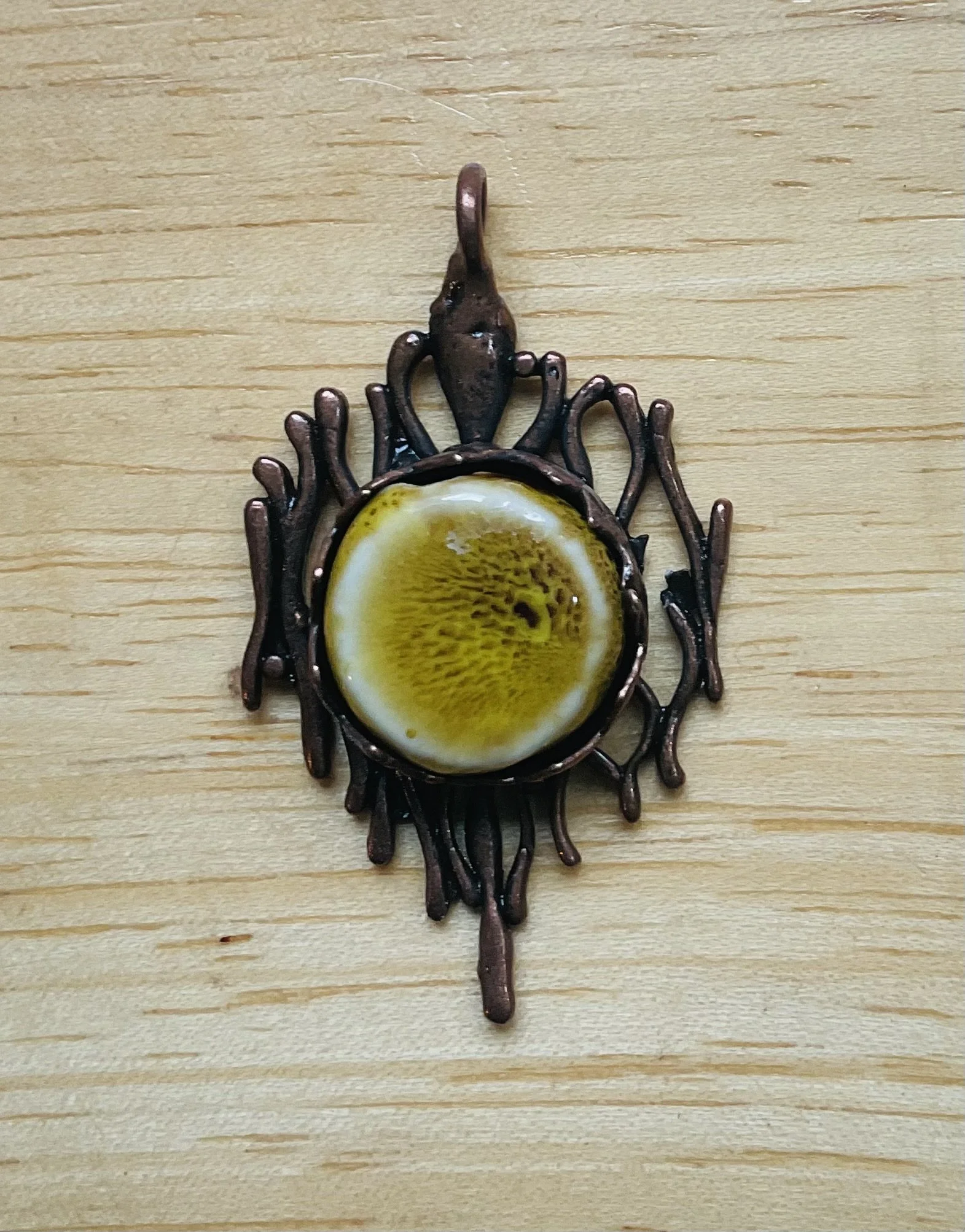 Bronze finished pendant filled with ceramic bead 40mm long