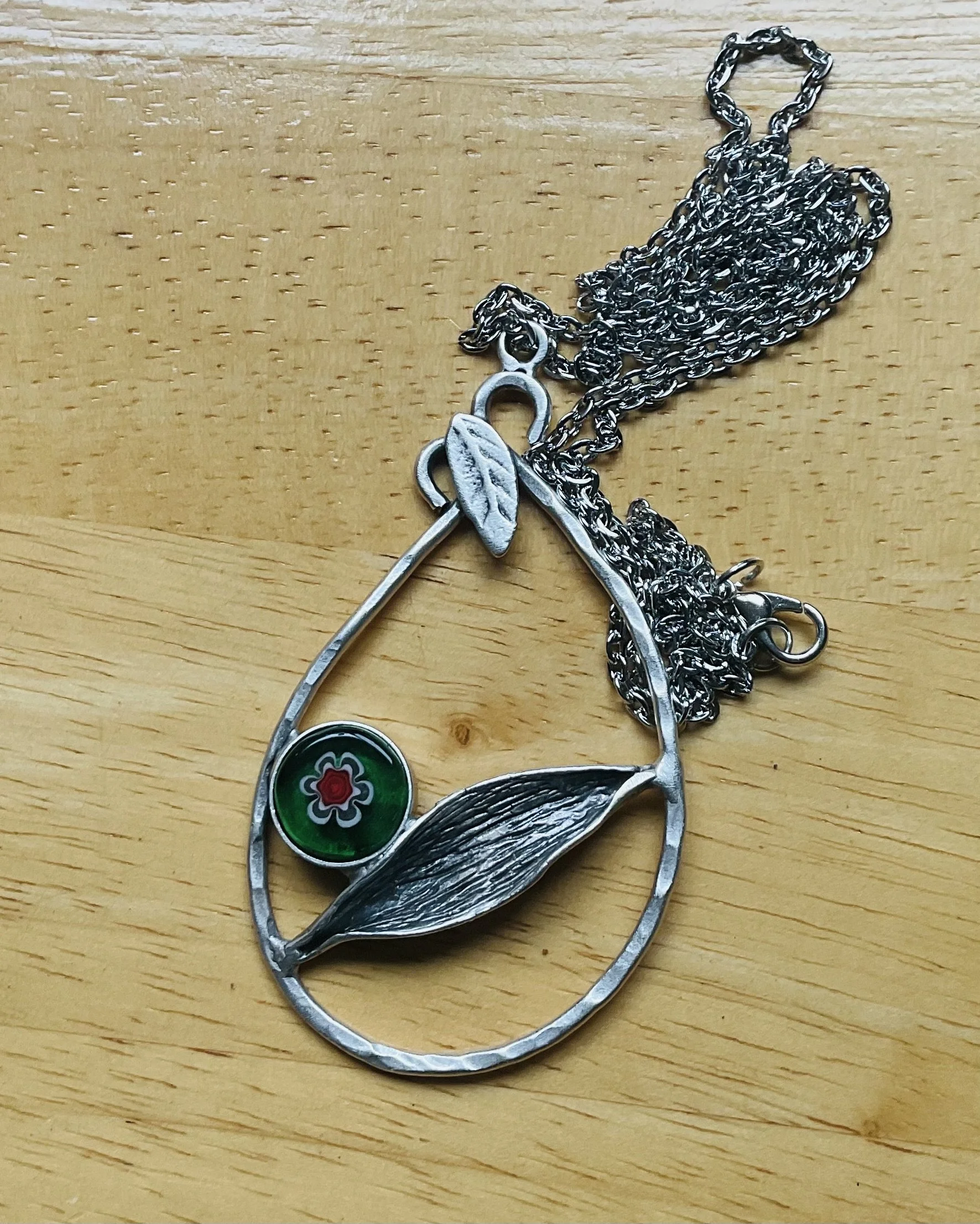 Silver coloured metal pendant 70mm long with a floral millifiori 