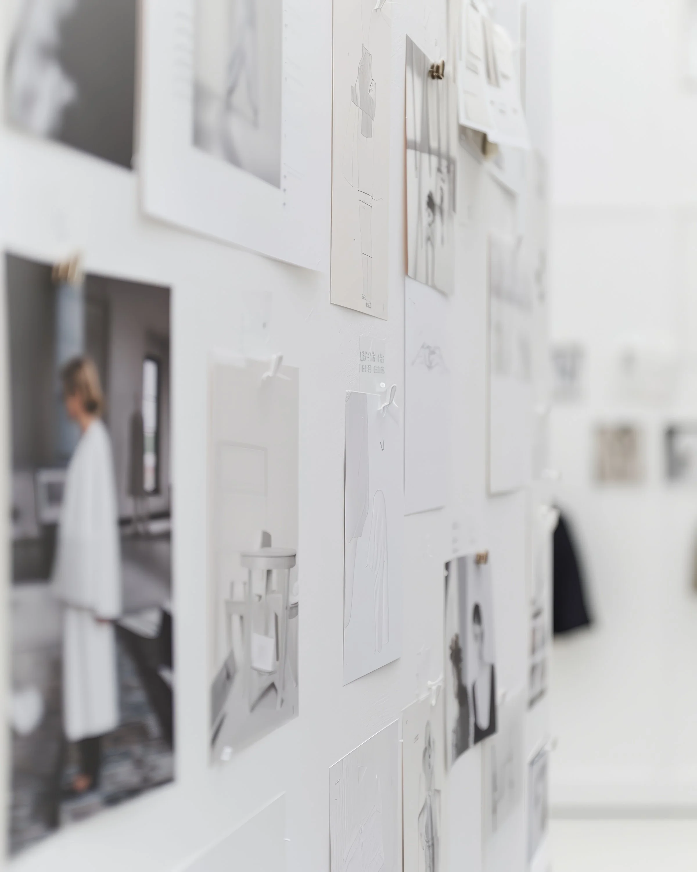 A wall covered with pinned black and white photos and sketches in a studio setting.