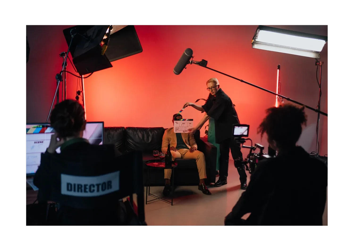 Film crew preparing a studio scene with a camera, lighting, boom microphone and clapperboard.