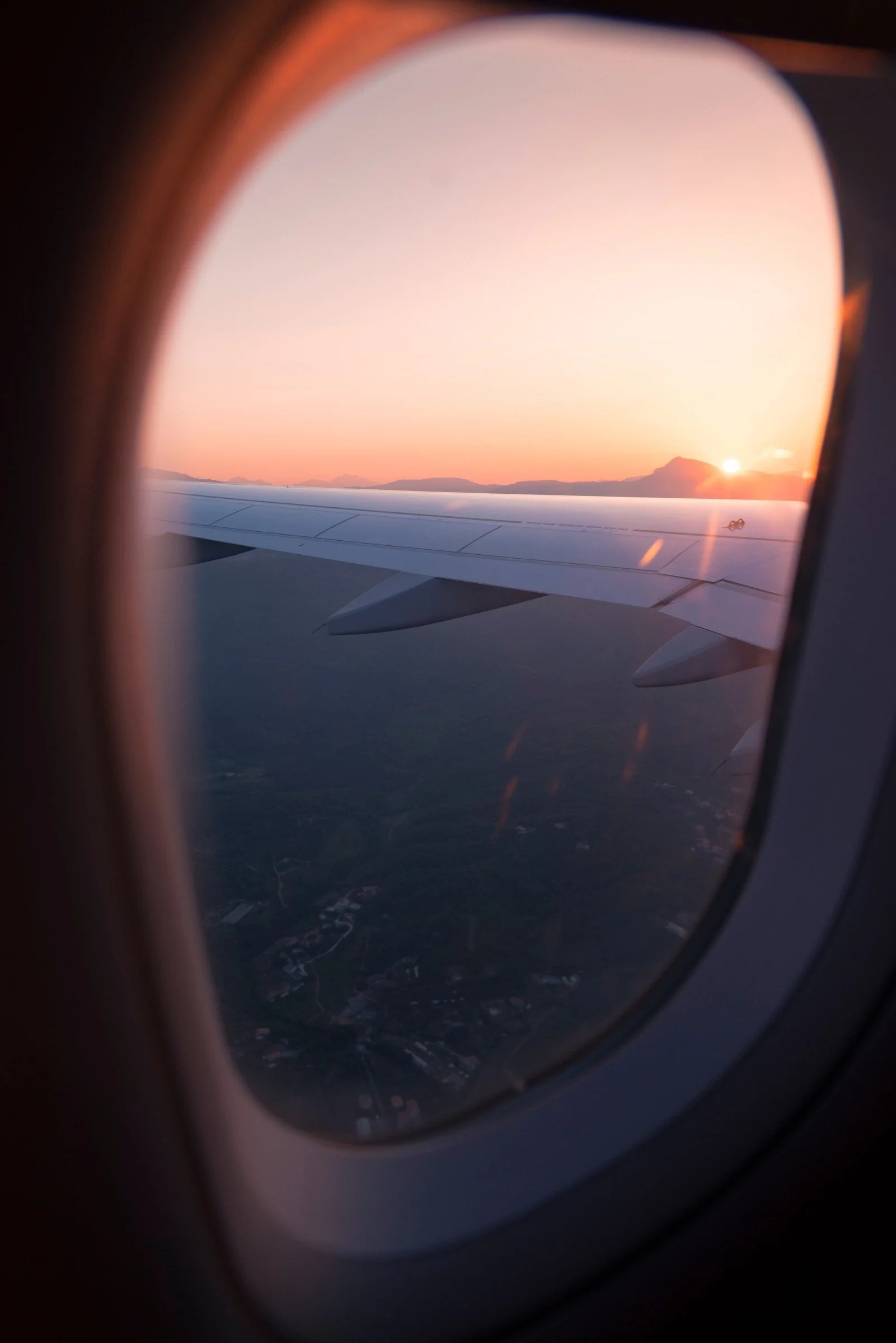 Sunset and an airplane wing seen through a cabin window