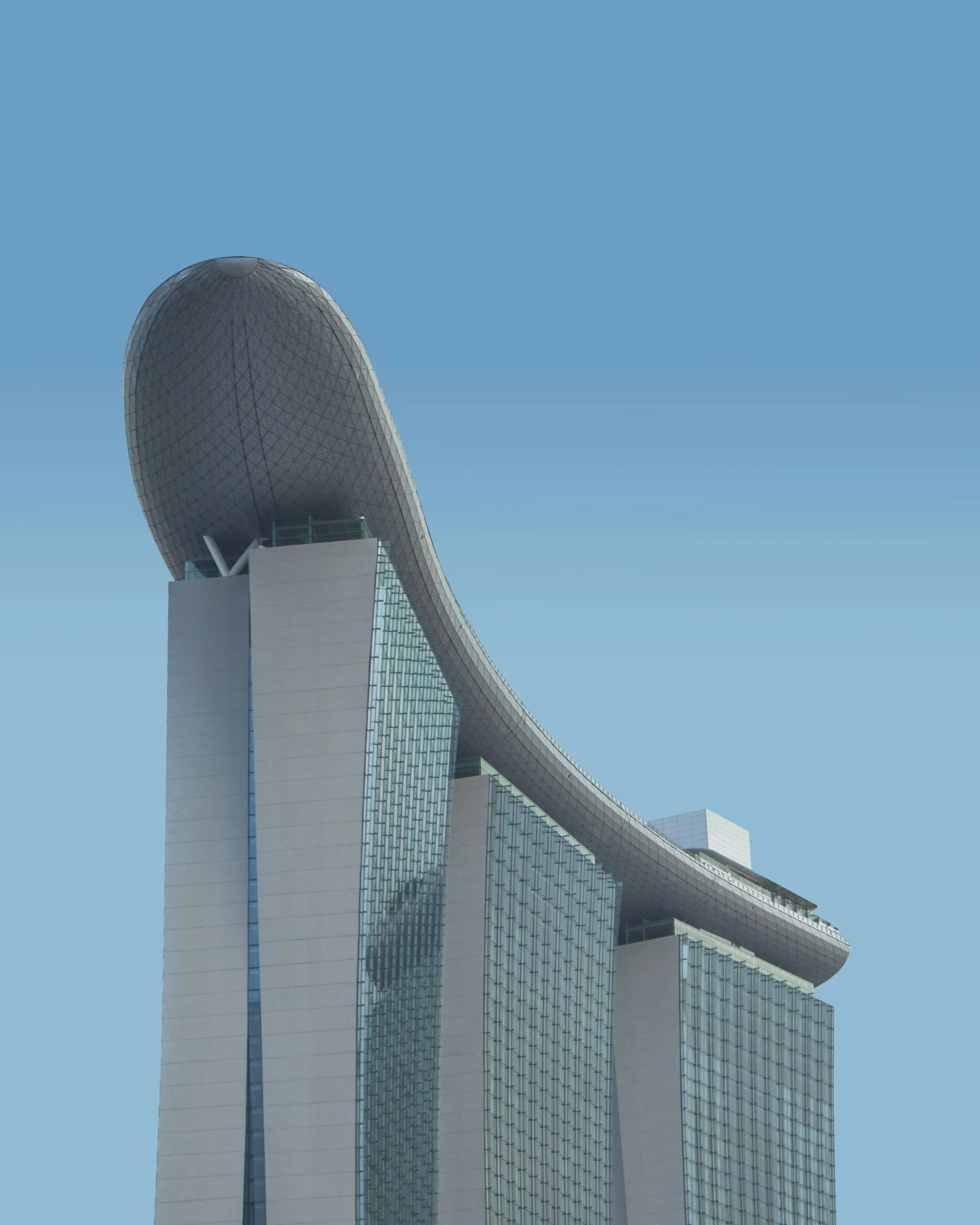 A tall, modern skyscraper with a curved, egg-shaped top and reflective glass windows, set against a clear blue sky.