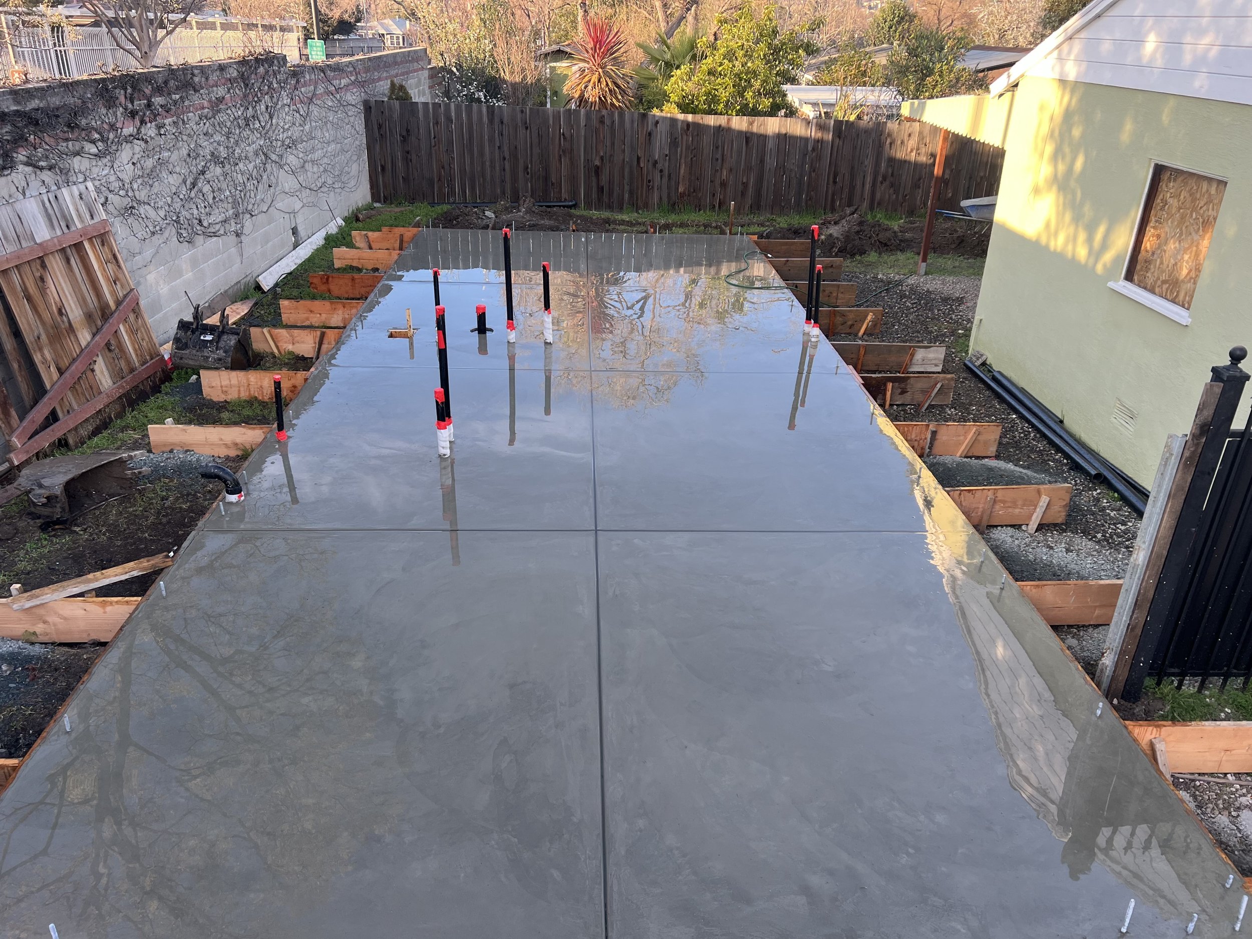 Fresh concrete slab in backyard with plumbing pipes