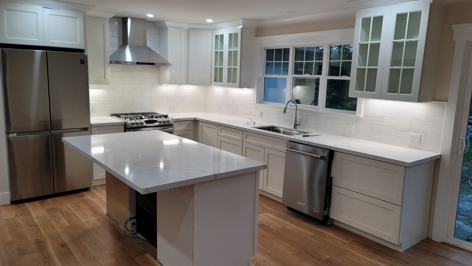 Modern kitchen with white cabinetry, stainless steel appliances, and a marble island.