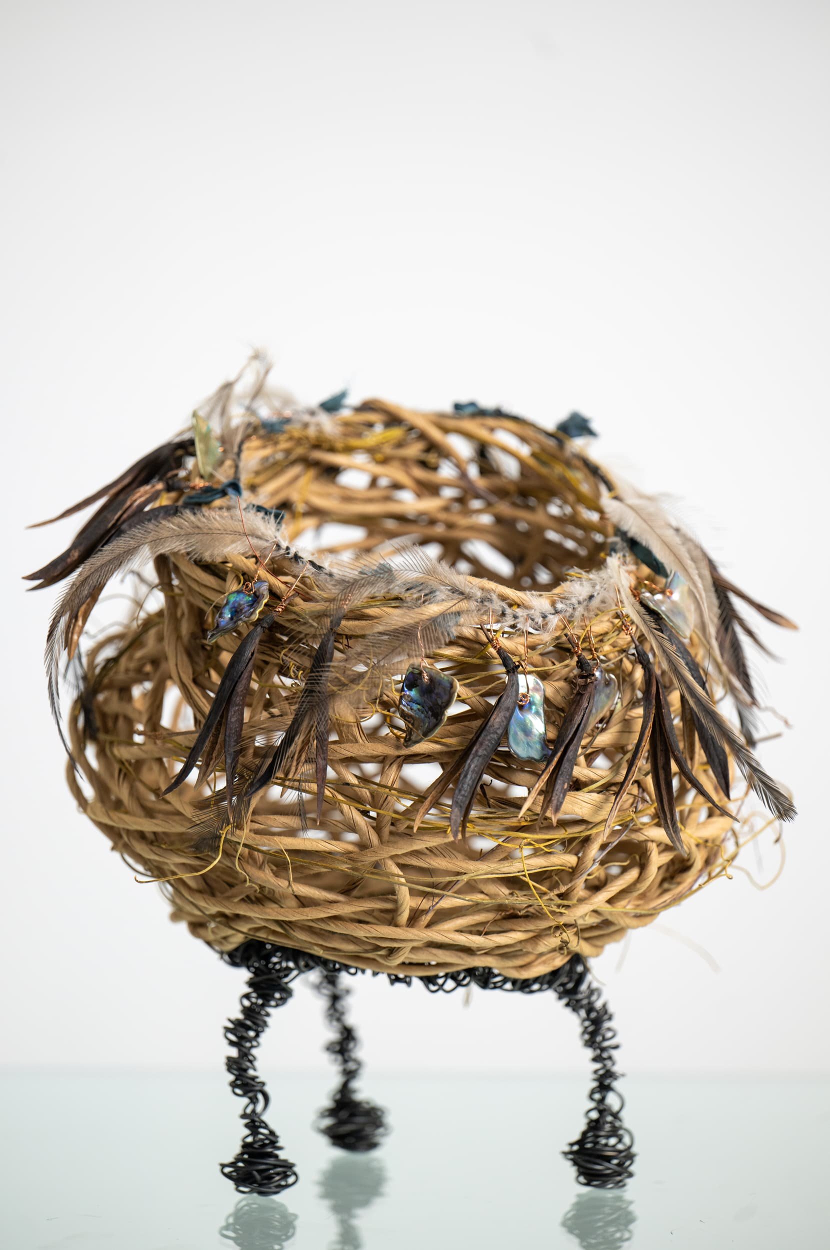 Random weave basket made with paper rope, dodder vine, wire, New Zealand paua shell, flax flower seed heads, and Australian emu feathers.