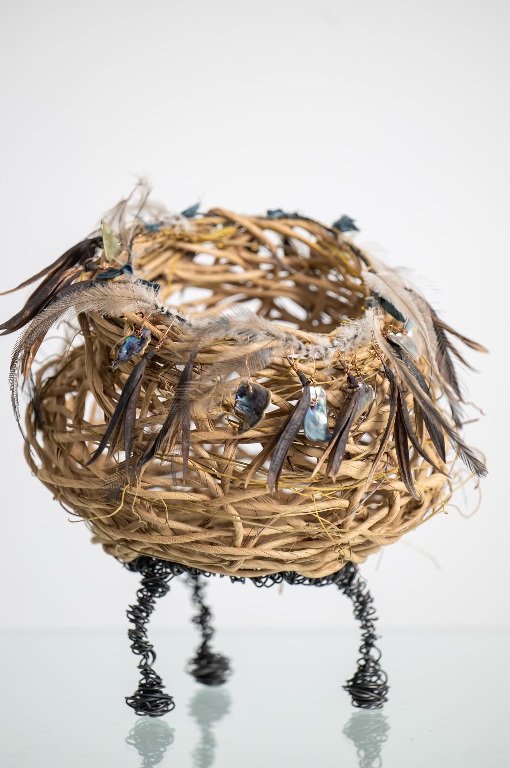 Random weave basket made with paper rope, dodder vine, wire, New Zealand paua shell, flax flower seed heads, and Australian emu feathers.