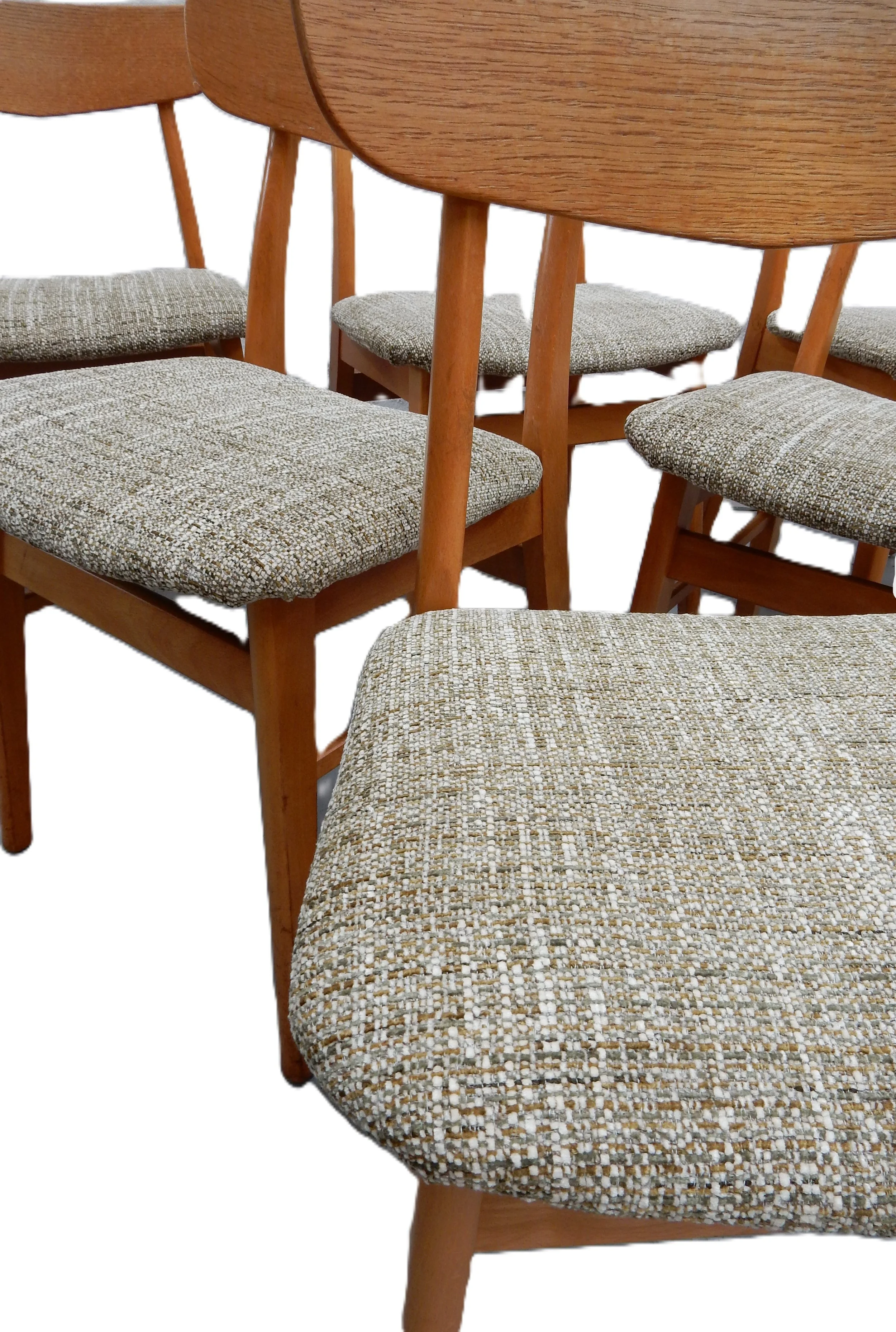 Close-up of a wooden dining table with four matching chairs featuring patterned fabric cushions on the seats, set against a white background.