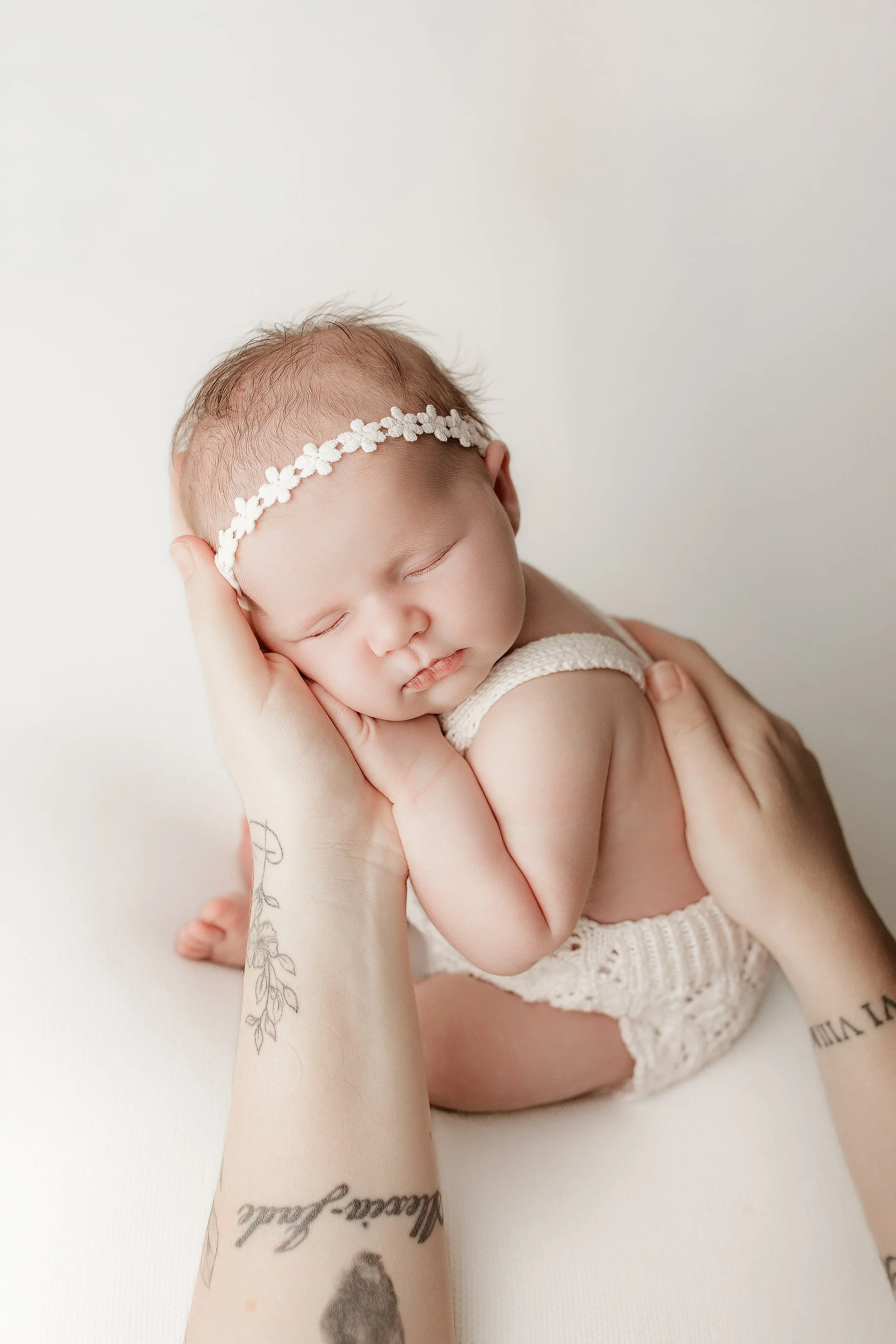 Newborn baby held by mum with soft neutral styling in Ipswich studio