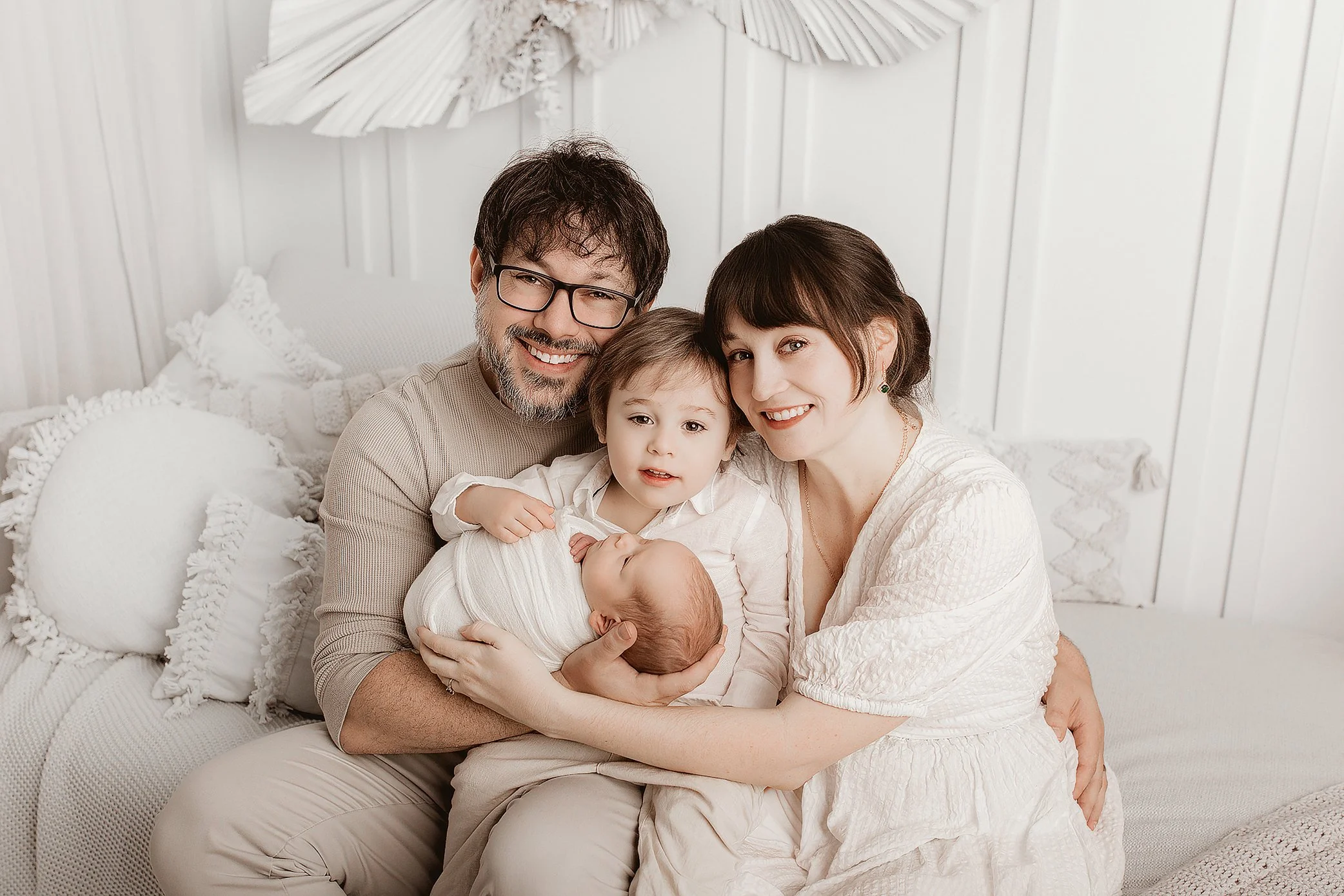Big sister gently holding newborn baby in Ipswich studio portrait