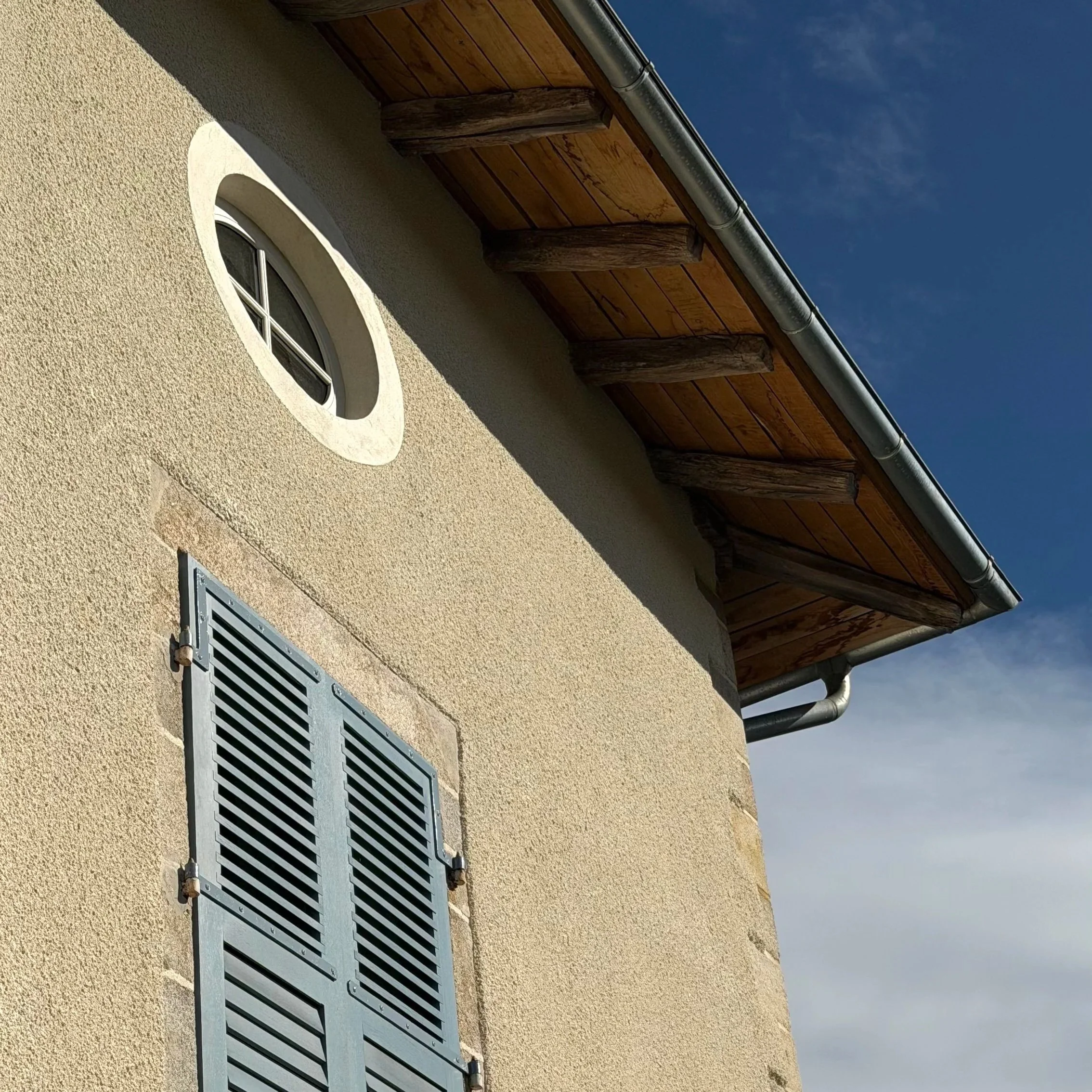 Œil-de-bœuf en bois sur mesure dans une façade enduite