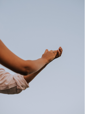 Person's arms reaching toward the sky against a clear background.