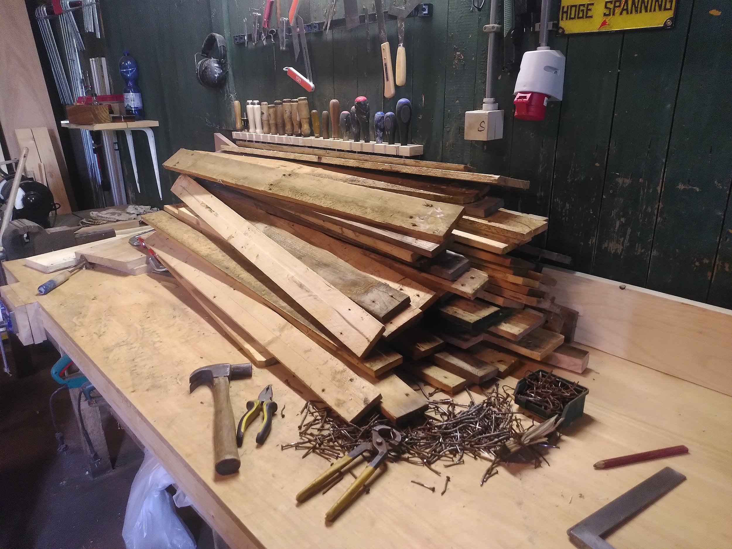 Gedemonteerd hout van pallets in de werkplaats van meubelmakerij MaaK Michael