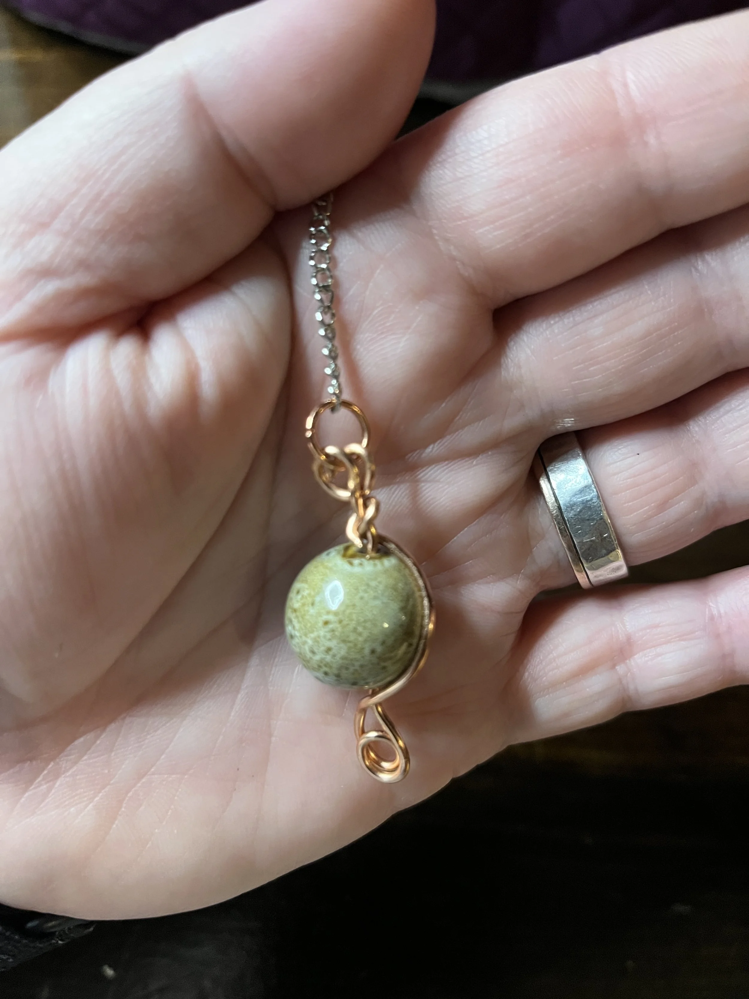 brown ceramic pendulum held in hand