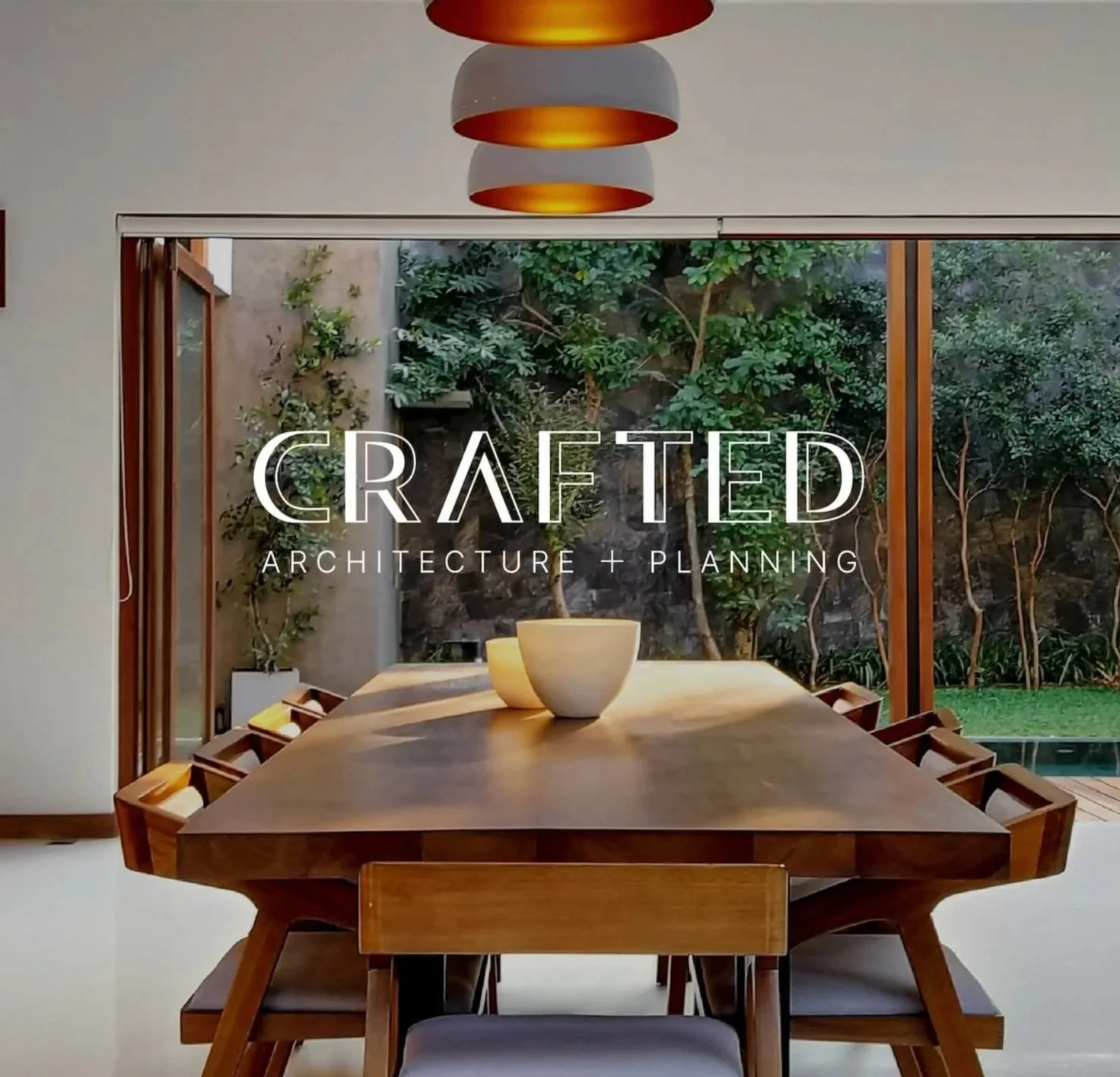 Inverted logo for 'Crafted Architecture + Planning' against an image of a modern interior dining room with a wooden table and chairs