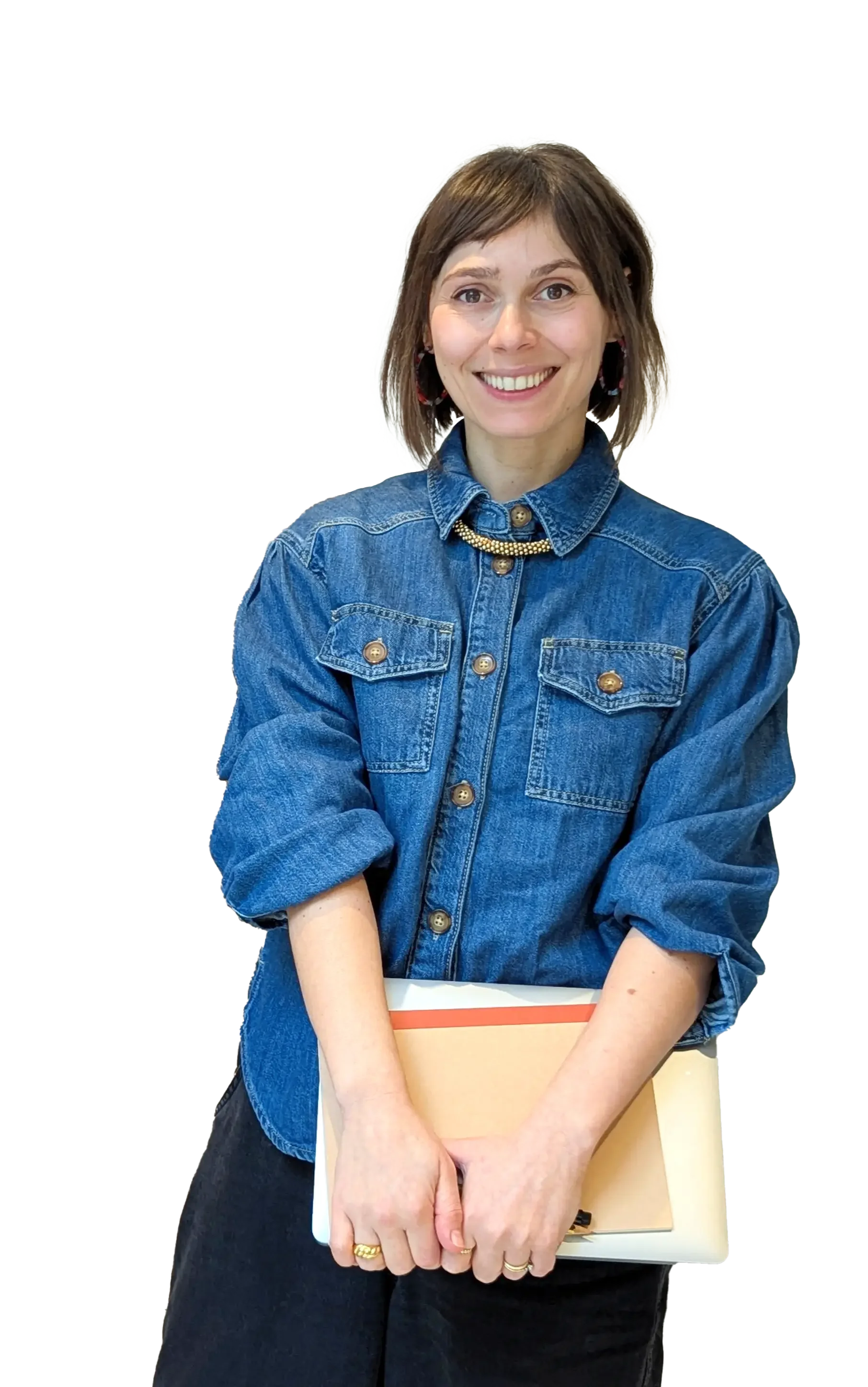 A full length shot of Tanya Coyle, Squarespace website designer, standing smiling and holding a closed laptop and notebook against her.