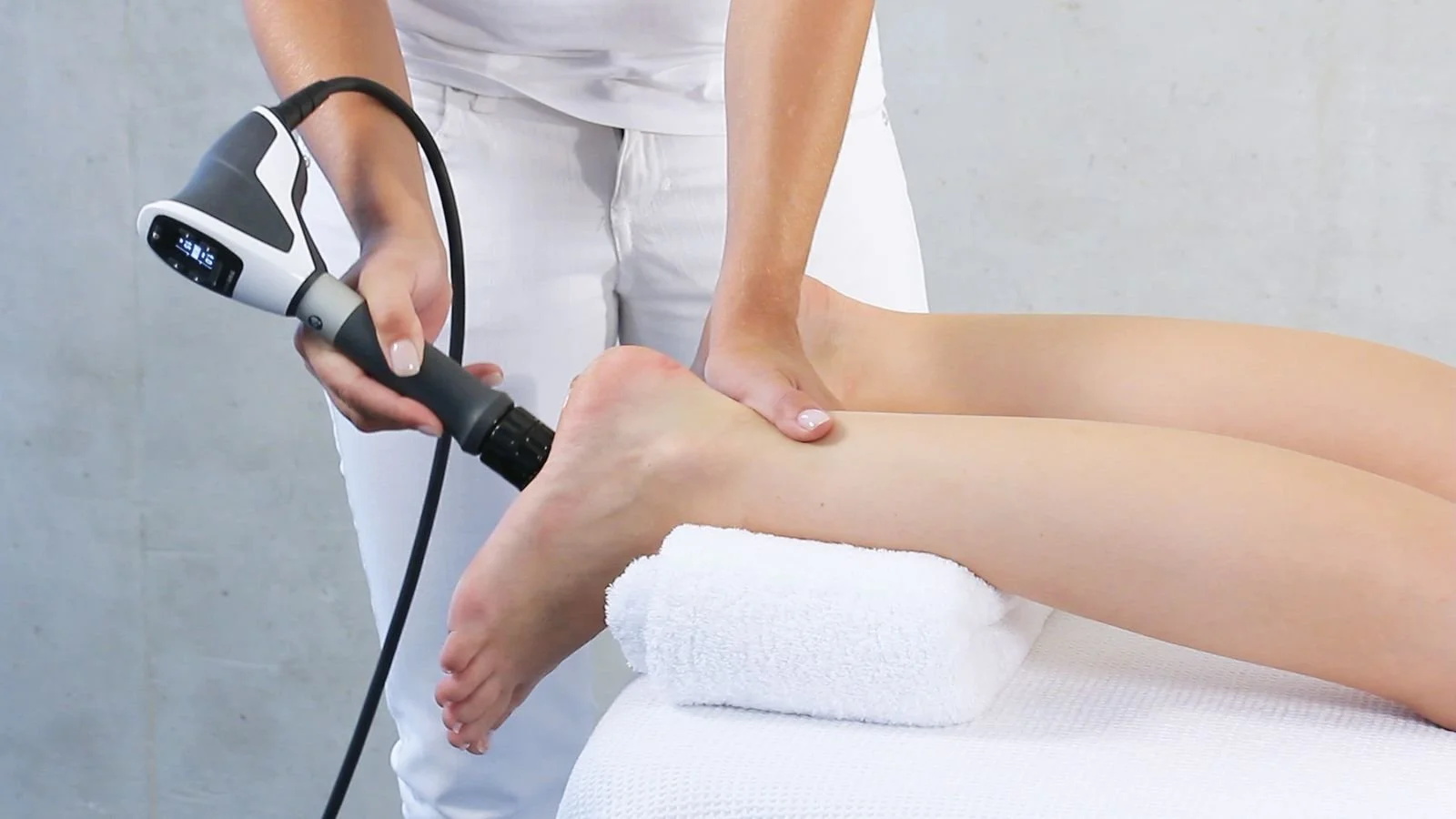 A person is receiving a cupping therapy on their lower leg from a therapist holding a device to create suction.