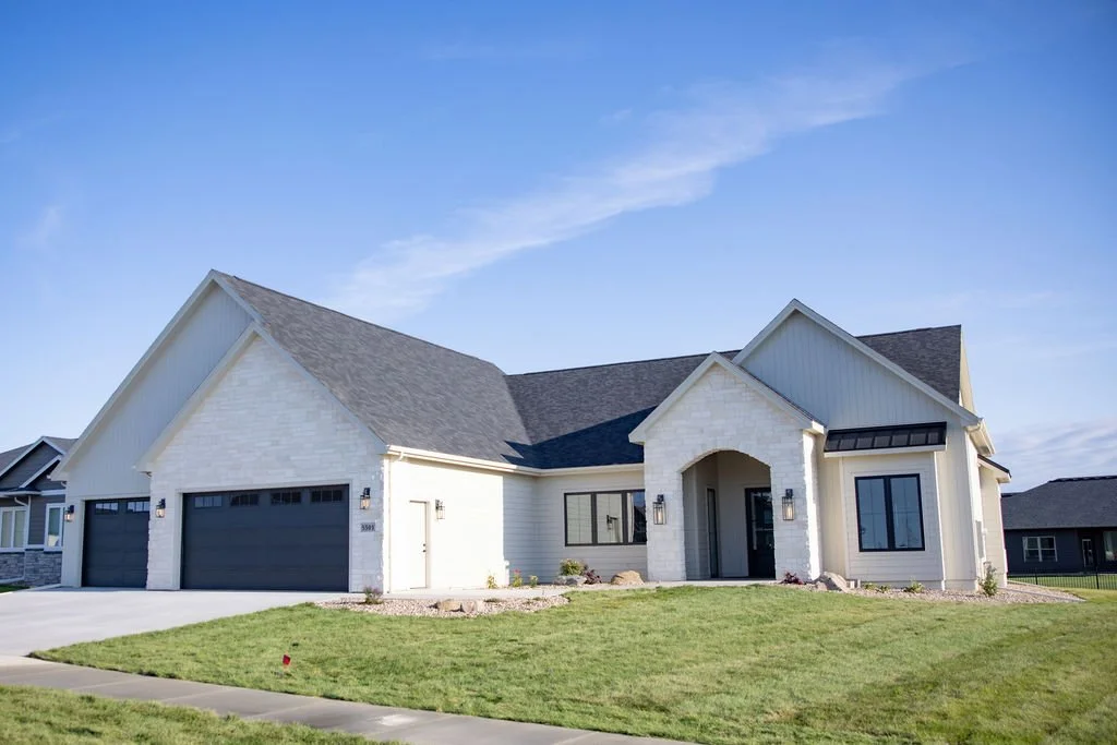 Partially constructed wooden house with exposed framing and trusses, blue sky background. Custom Home builder in Sioux Falls, SD