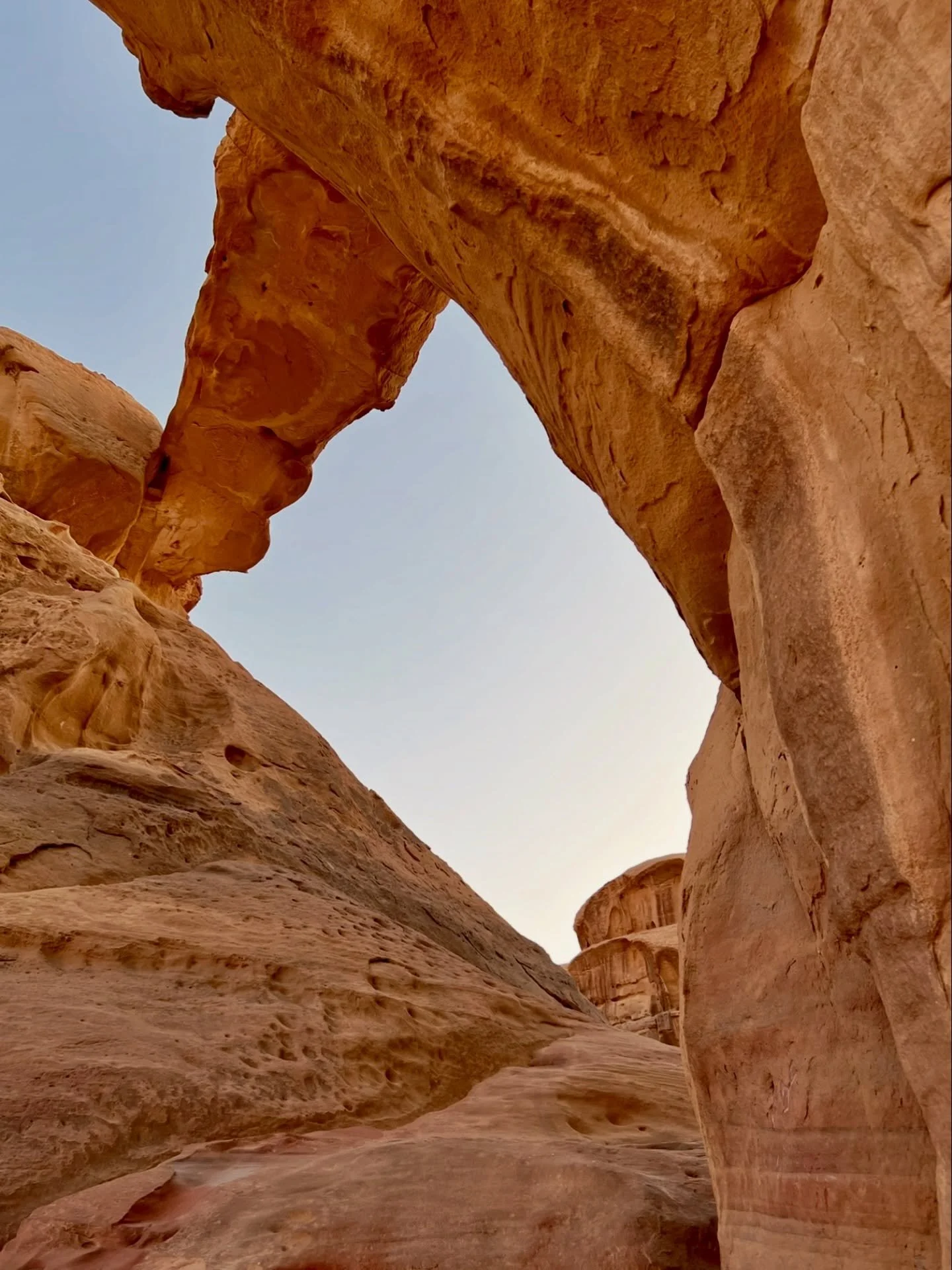 Hiked into Wadi Rum at dawn. It is a sandstone and granite desert in southern Jordan.

This arch formed through differential erosion, where wind and temperature variations wore soft rock layers down. What remains is accidental structure: compression,