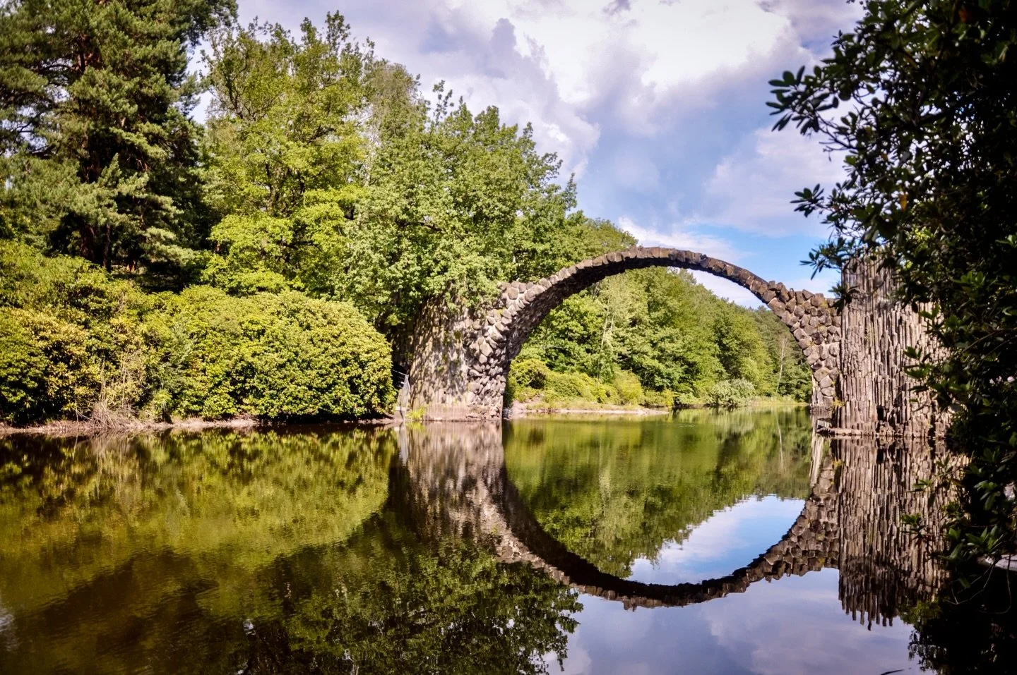 Rakotzbr&uuml;cke, Saxony, Germany. 

Built between 1866 and 1875 within the landscaped grounds of Kromlauer Park, commissioned by estate owner Friedrich Hermann R&ouml;tschke. The slender stone arch spans 19.8 meters across the artificial Rakotzsee 