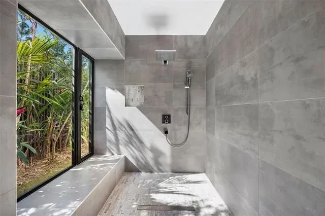 Luxury walk-in shower with elegant gray tiles, large glass doors, and a modern rainfall showerhead