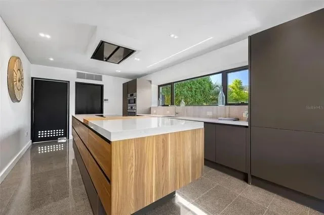 Spacious luxury kitchen renovation featuring modern cabinetry, a large center island, high-end stainless steel appliances