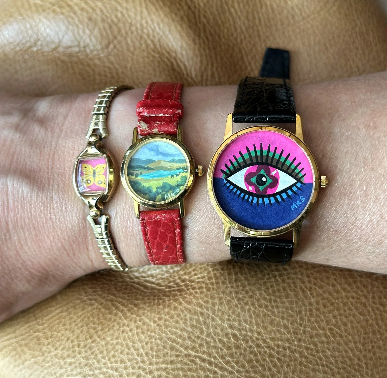 Art bracelets with butterfly, landscape, and eye.