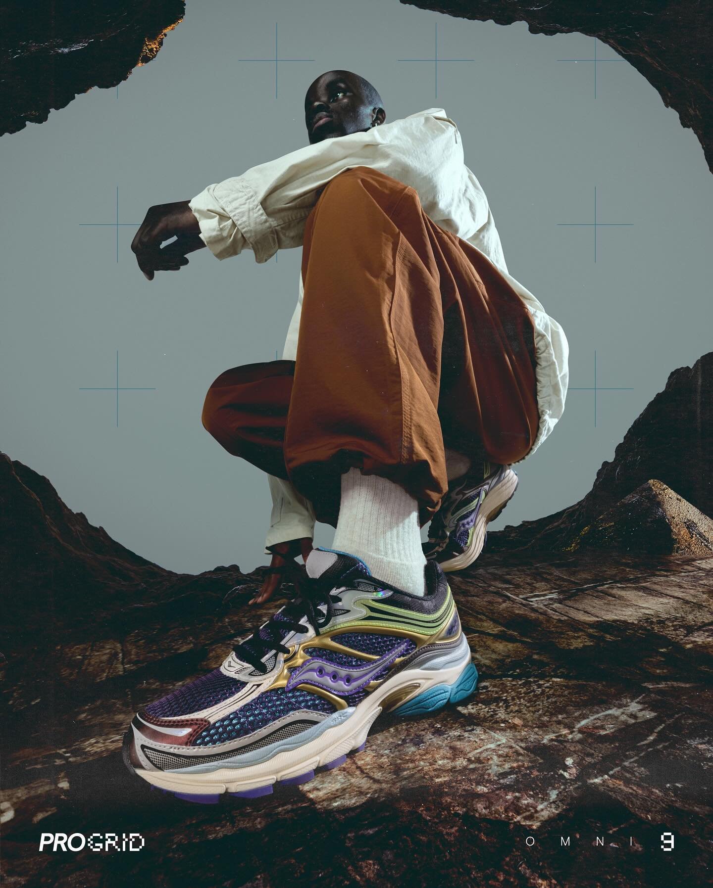 A low-angle shot of a person crouching amidst rocky terrain, wearing colorful athletic shoes, white socks, brown pants, and a white shirt with a gray background.