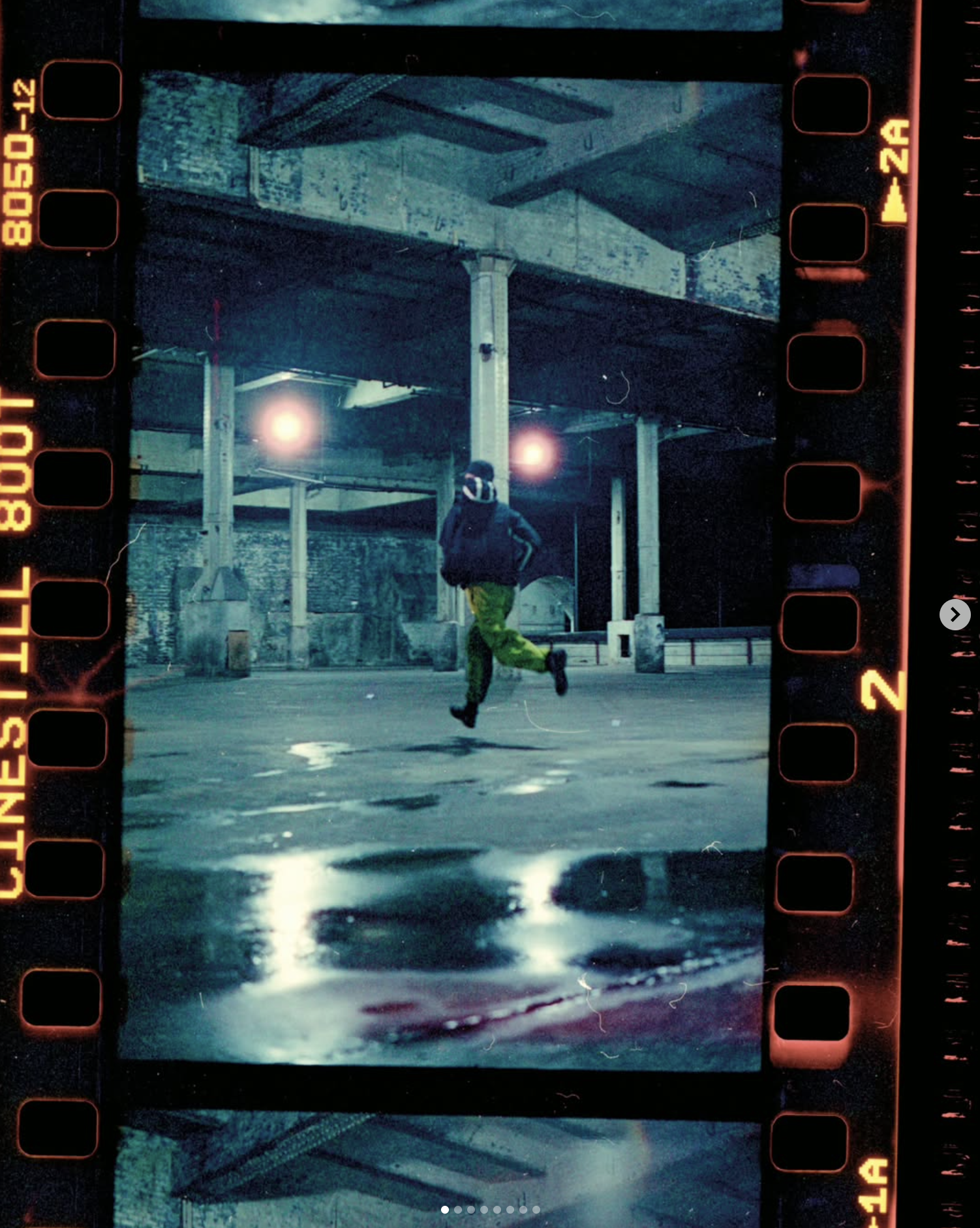 A person running under an overpass at night, with wet ground reflecting lights, and illuminated by bright streetlights.
