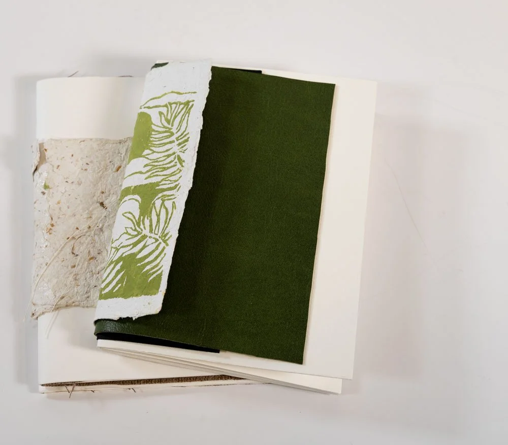 Une pile de papiers, de carton et de tissu avec différentes textures et couleurs, sur un fond blanc.