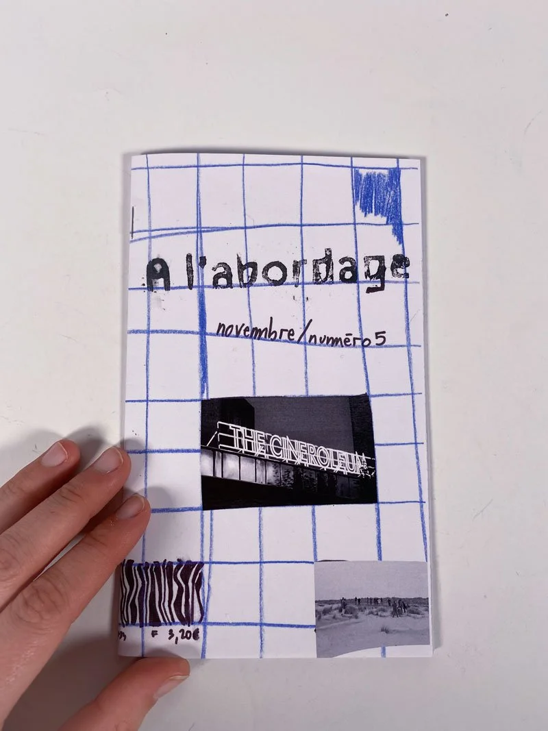 Page de carnet avec texte "Allabordage" et "novembre / numéro 5", un collage de photo noir et blanc, un code-barres, et un dessin de grille bleue.