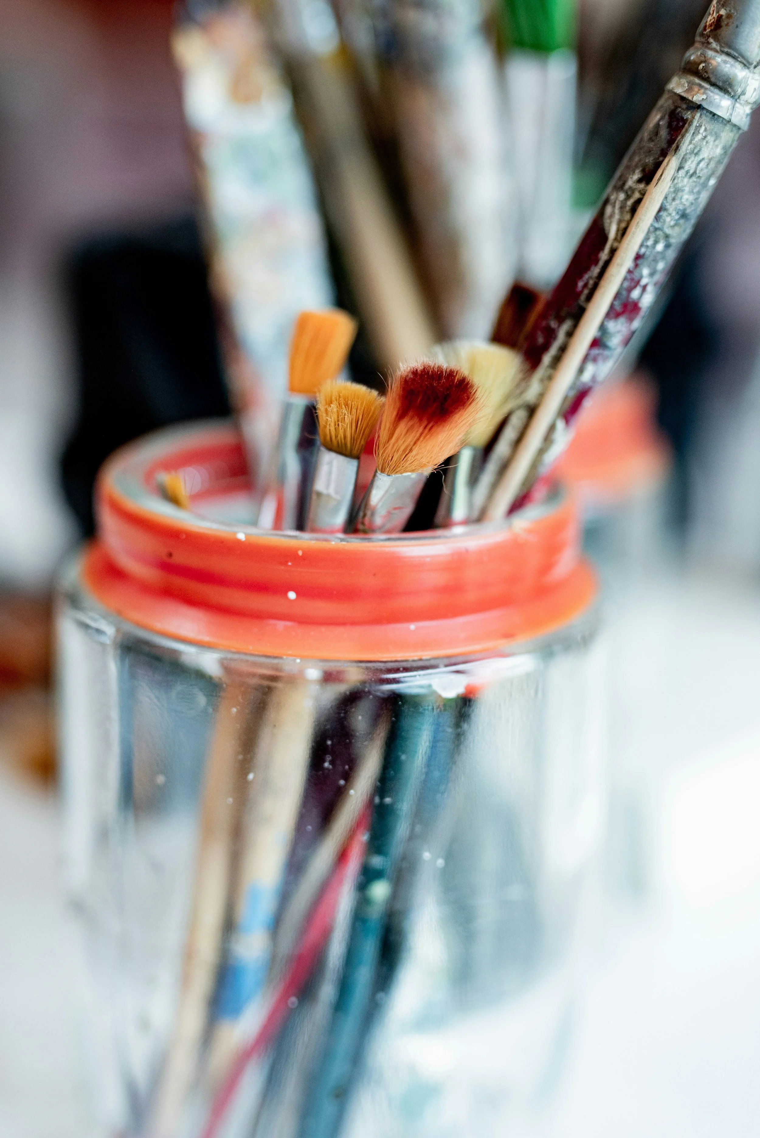 Jar of well-loved paintbrushes, symbolizing creativity, healing, and neurodivergent expression through art with Ember Studio