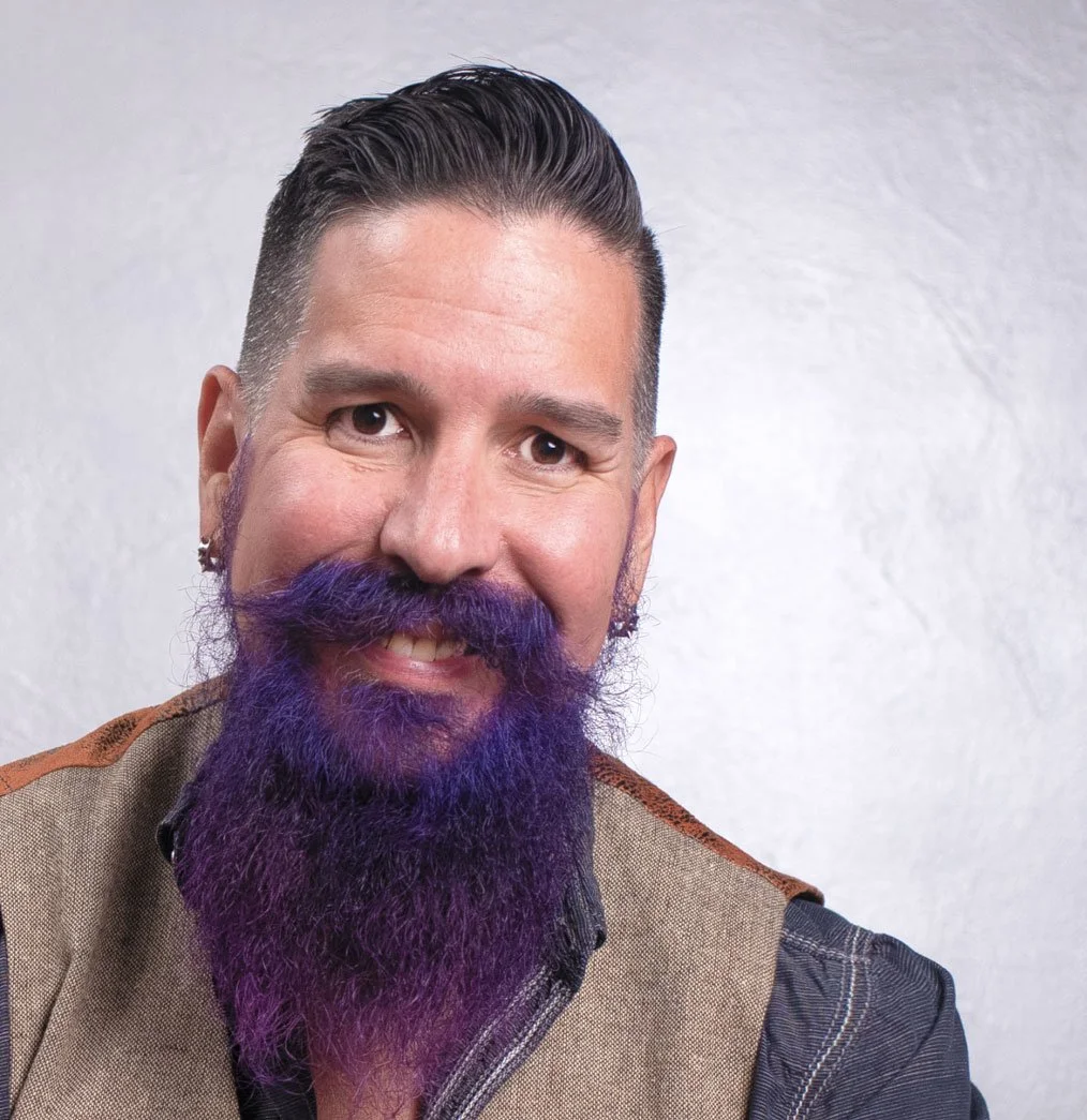 Dave Pereda, a middle aged dark haired man with a beard smiling headshot