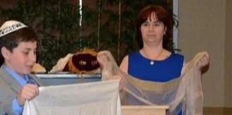 A boy and a woman holding a large piece of fabric or netting.