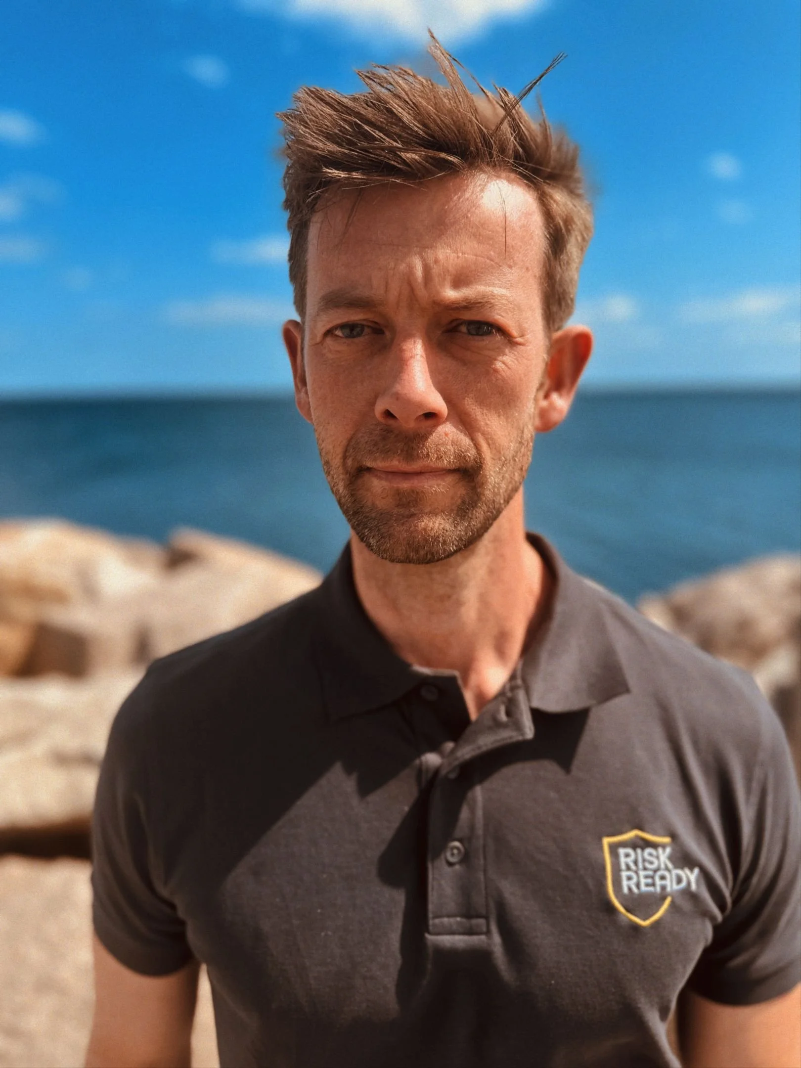 Paramediciner fra Risk Ready i firmapolo foran kystlinje – ekspert i beredskabsplanlægning.