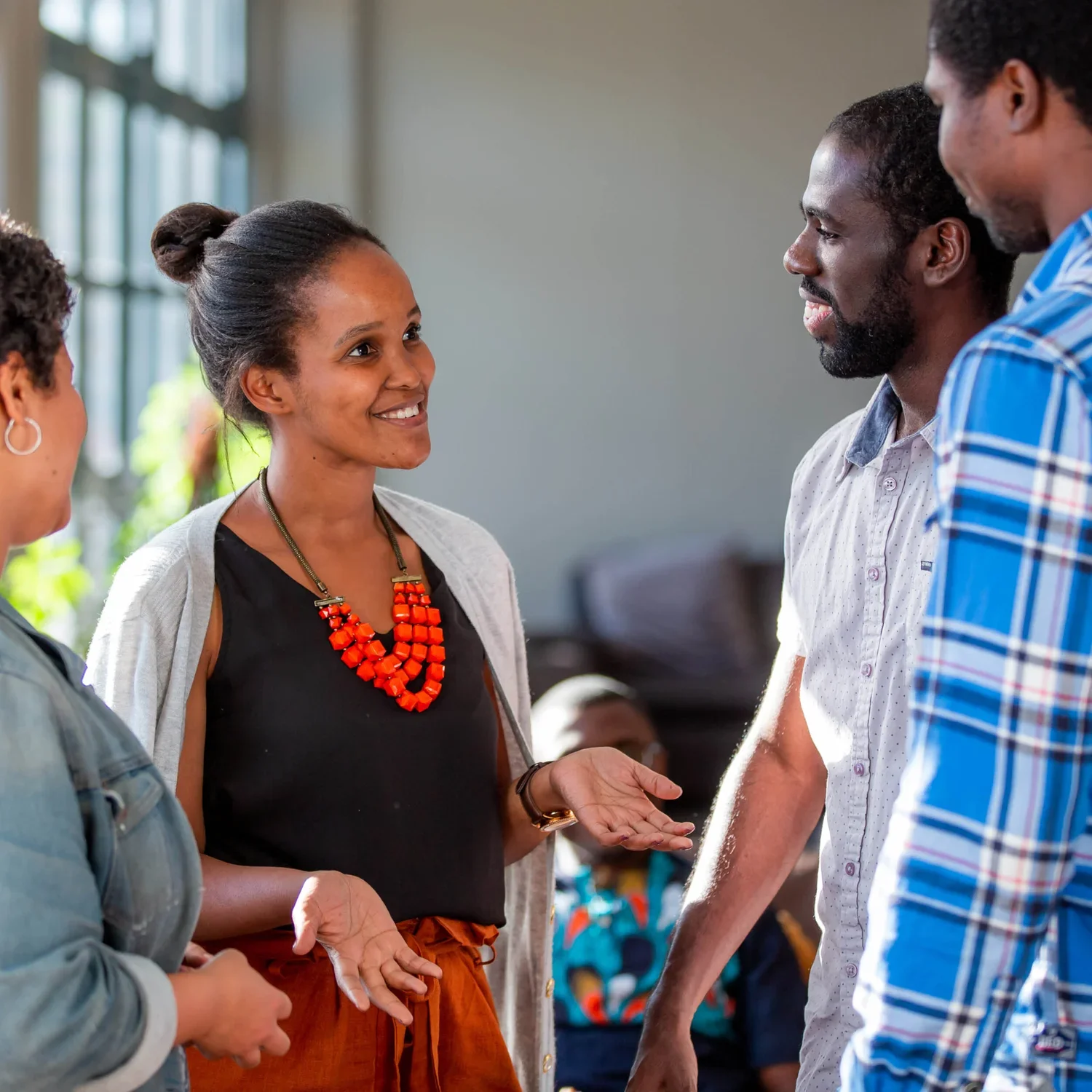 People gathered around a table in a cozy, rustic setting, engaging in conversation, with drinks and snacks on the table.