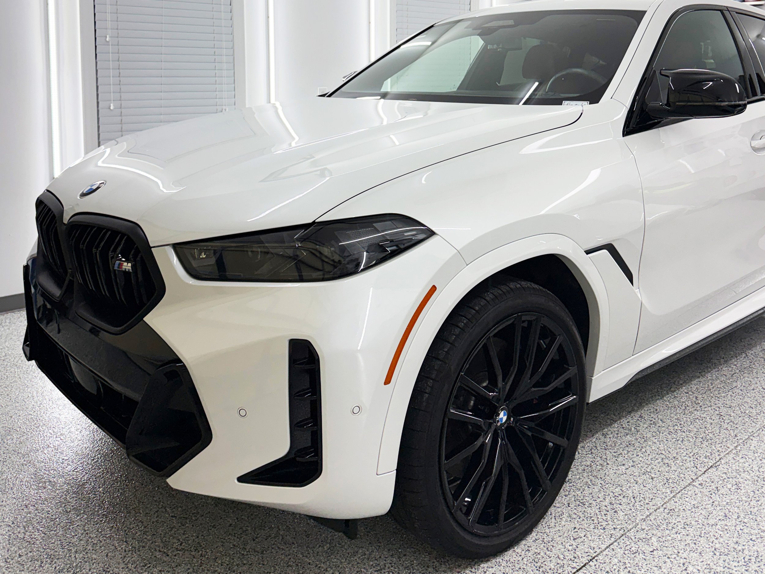 Black Audi SUV parked in a clean garage with tools hanging on the wall and a closed door in the background.