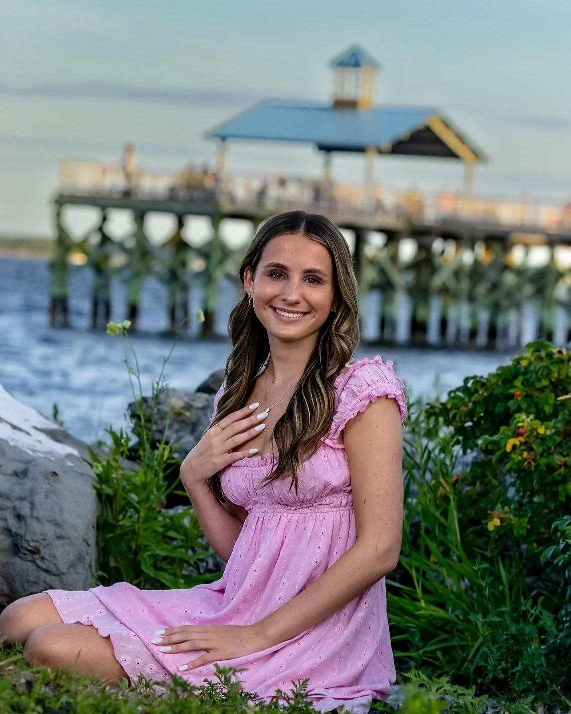 High school senior girl in a pink dress with the Rocky Point Pier.