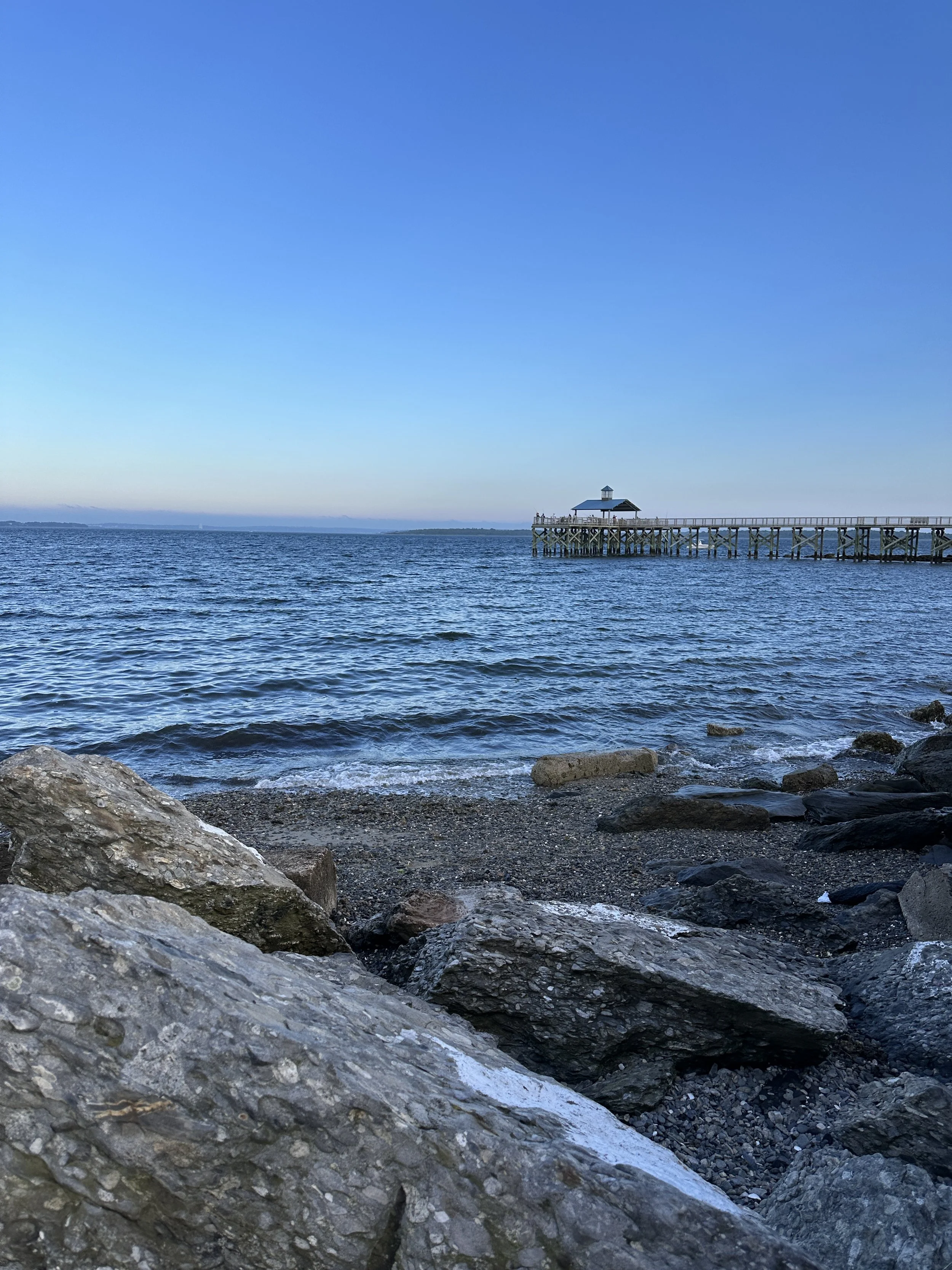 Rocky shoreline and pier overlooking Narragansett Bay at Rocky Point State Park in Warwick, Rhode Island.