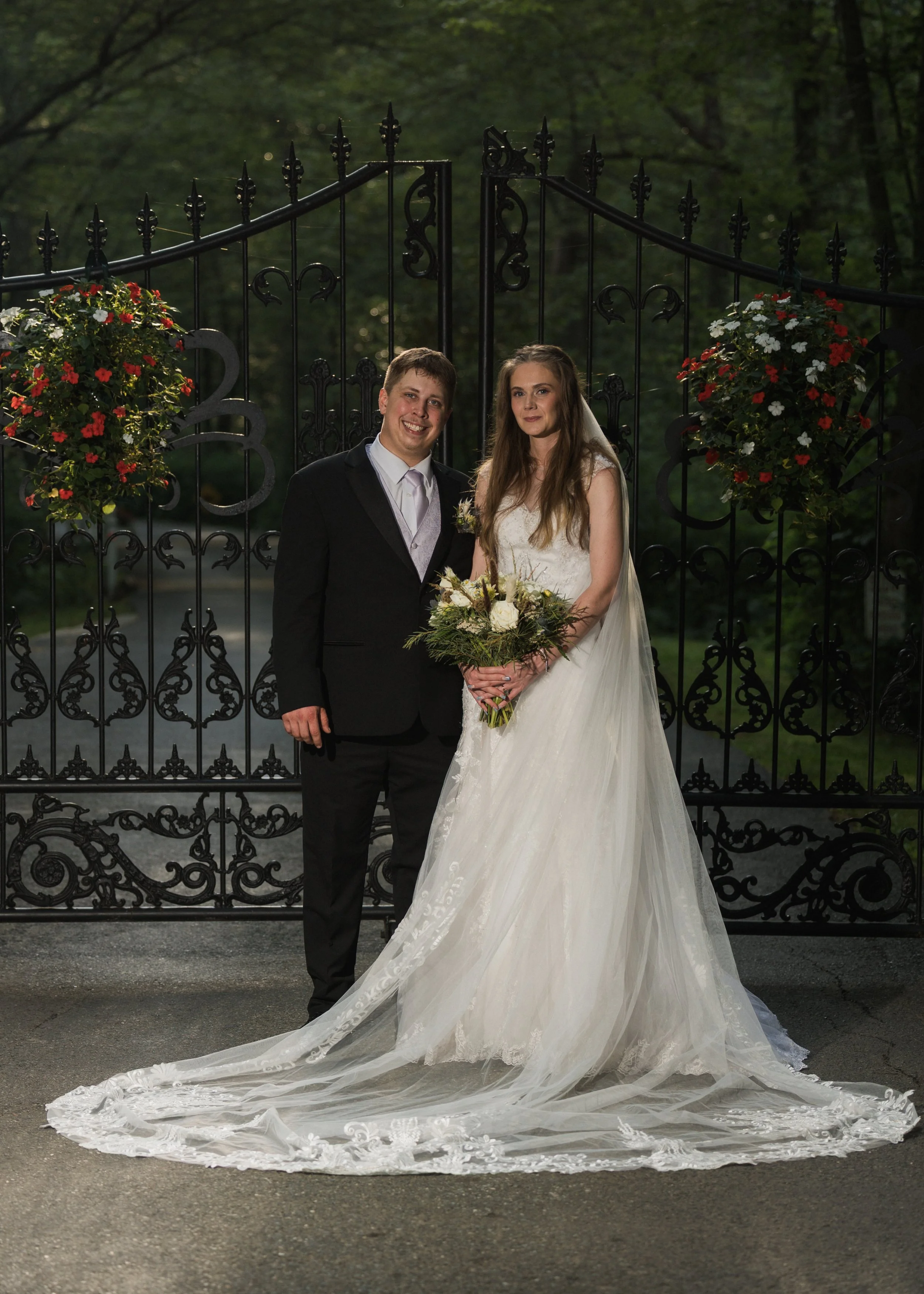 Bride and groom in front of the wrought iron gate at Five Bridge Inn in Rehoboth, Massachusetts.
