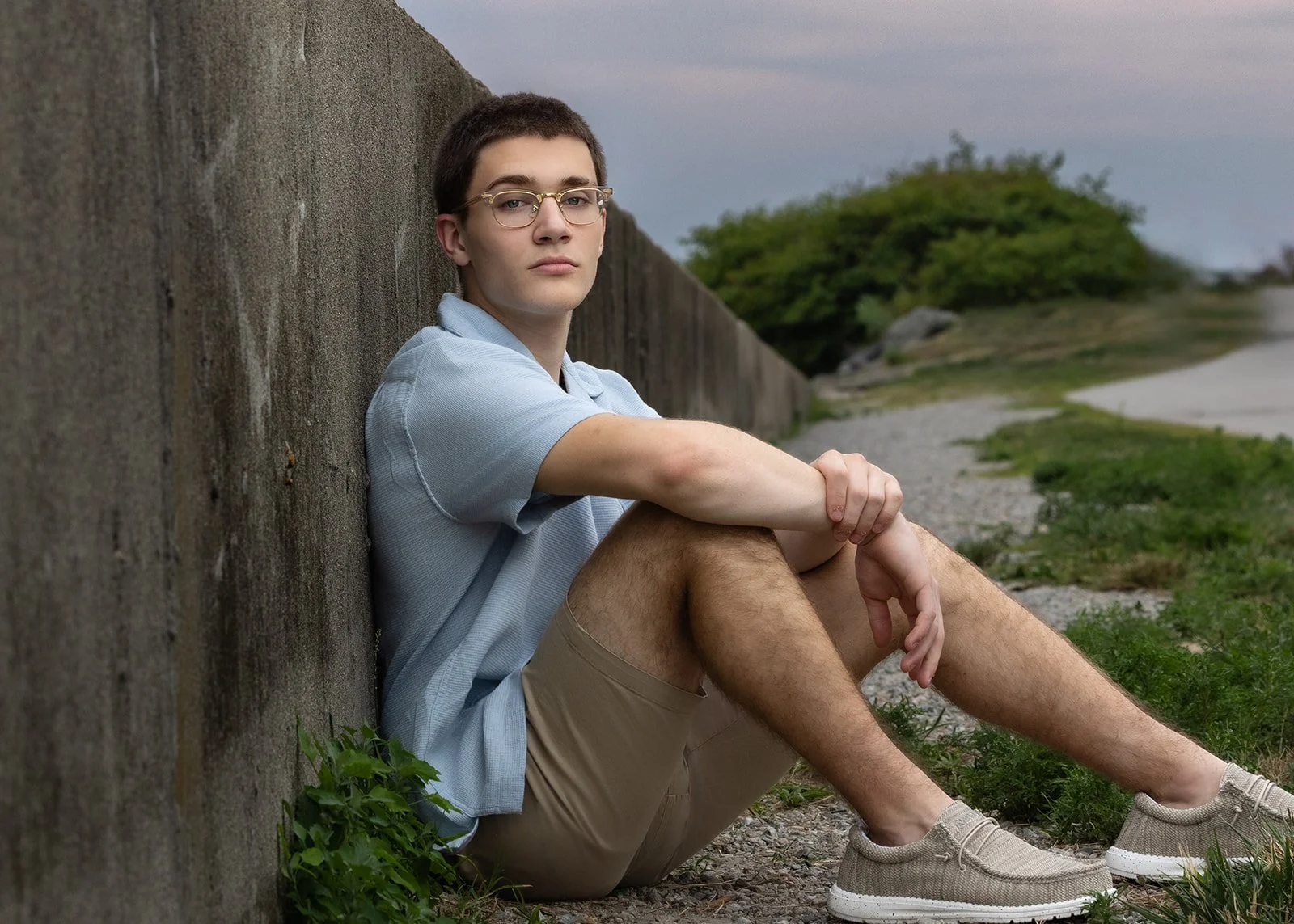 High School senior boy sitting against the wall at Rocky Point State Park in Warwick, Rhode Island.