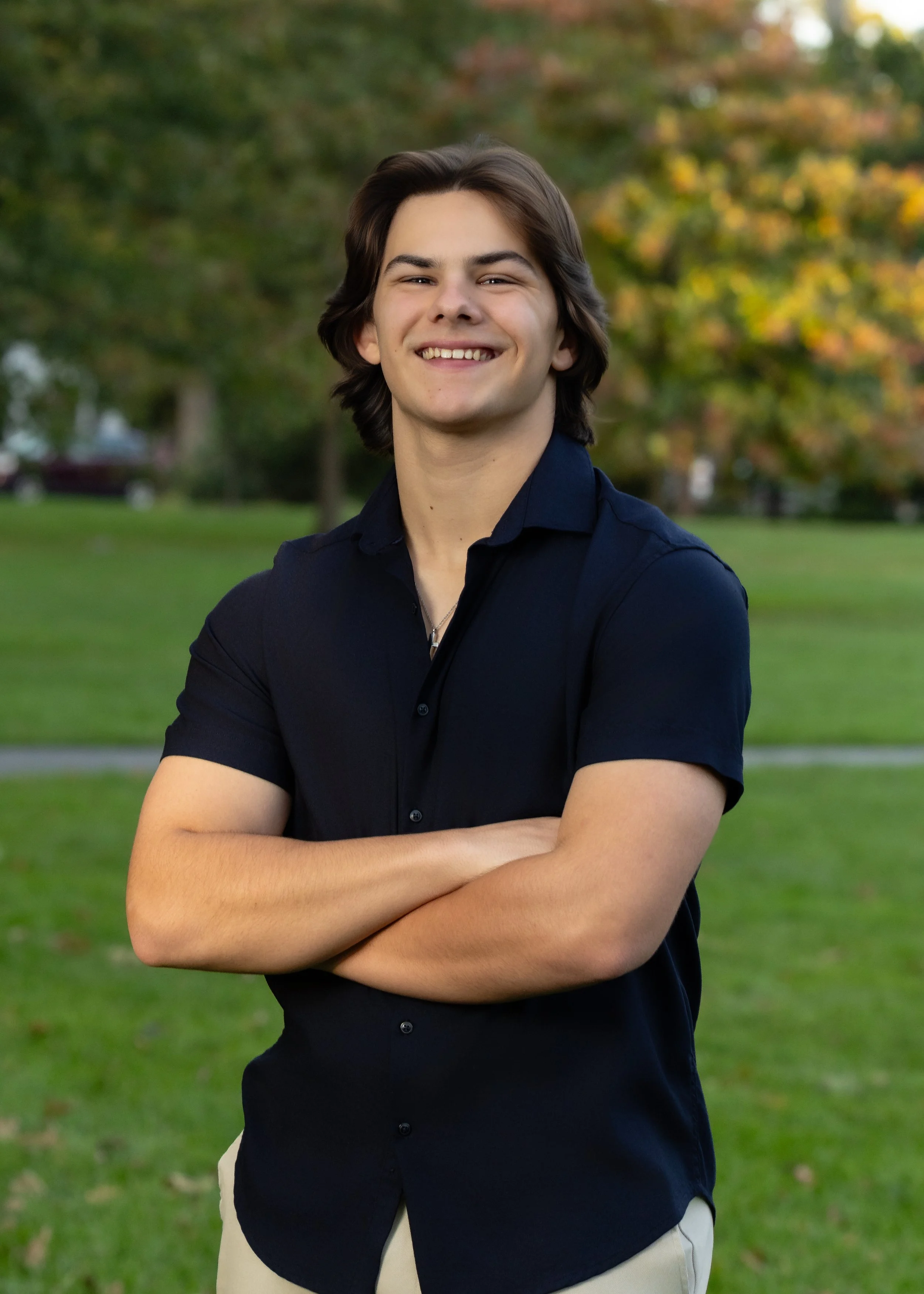 High school senior portrait of a boy standing outdoors in a grassy field in Massachusetts
