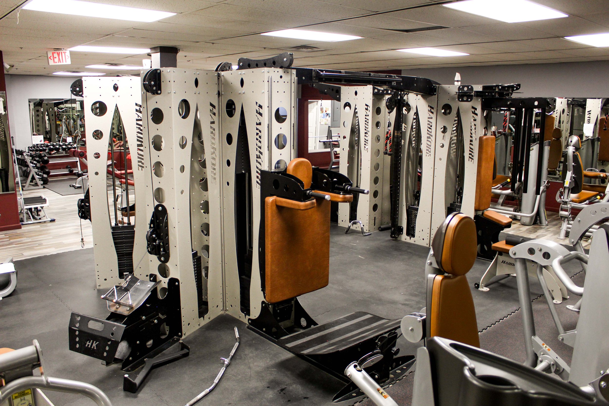 Modern jungle gym-style workout equipment with multiple stations for strength training, featuring leather-cushioned seats and handles in a spacious gym with a clean, professional atmosphere.
