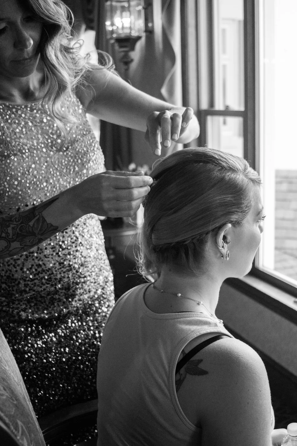Jess Puglia, hair designer and founder of The Hair Mansion in Reading, MA, styling a guest’s elegant updo during a wedding, showcasing her refined artistry and personal connection to each look.