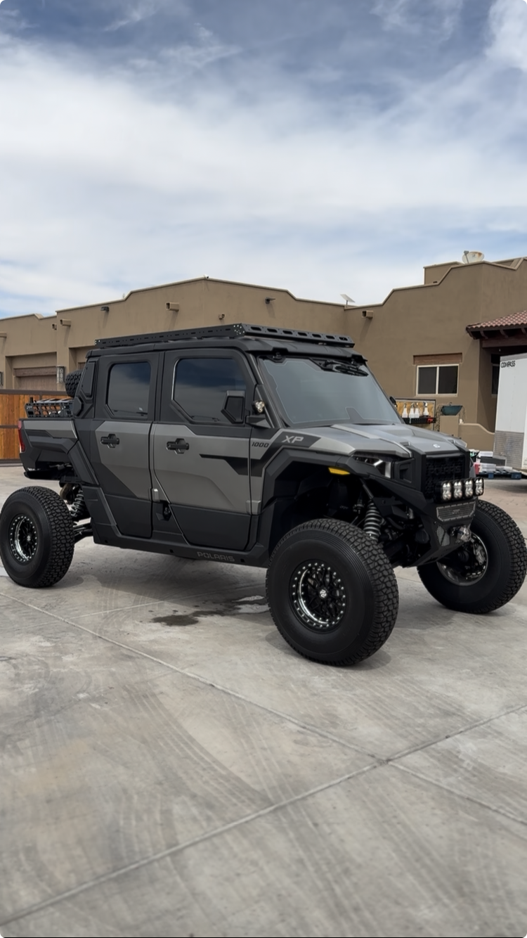 A black and gray off-road utility vehicle or ATV with large tires parked on a concrete driveway.