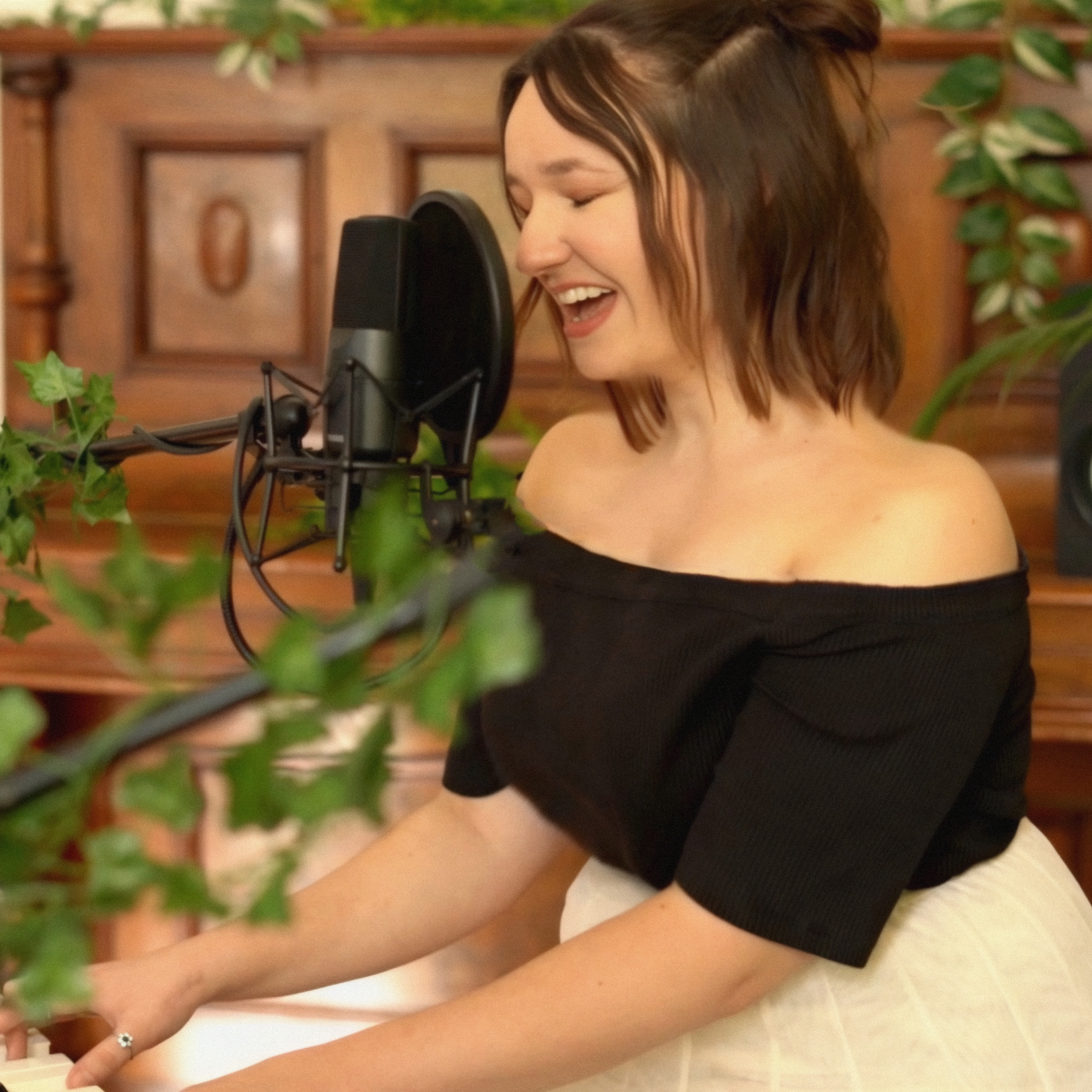 Eine junge Frau singt in einem Tonstudio, während sie an einem Klavier spielt.