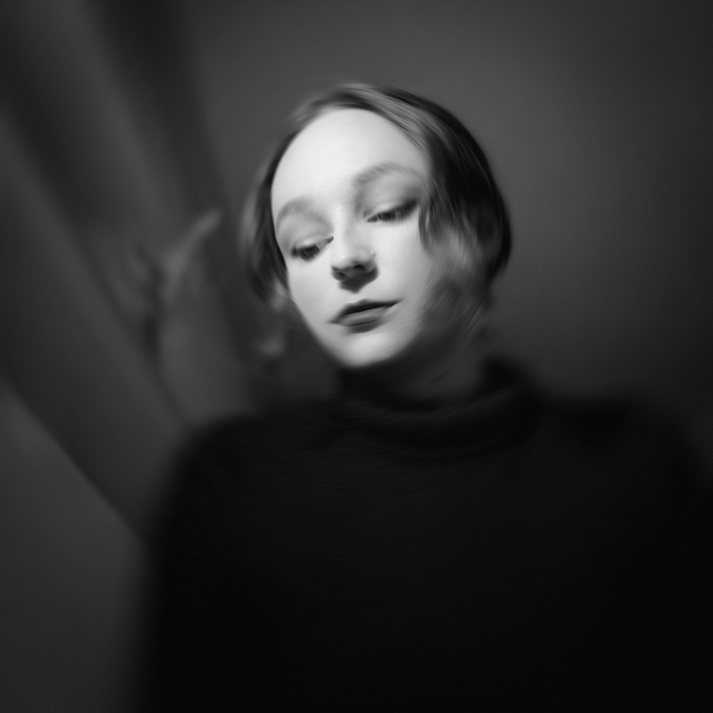 Ein schwarz-weiß Portraitfoto einer jungen Frau, deren Gesicht durch ein bewegtes oder unscharfes Glas verzerrt wird.