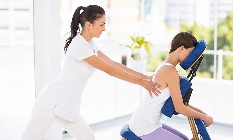 Physical therapist assisting a woman with a back massage on massage table
