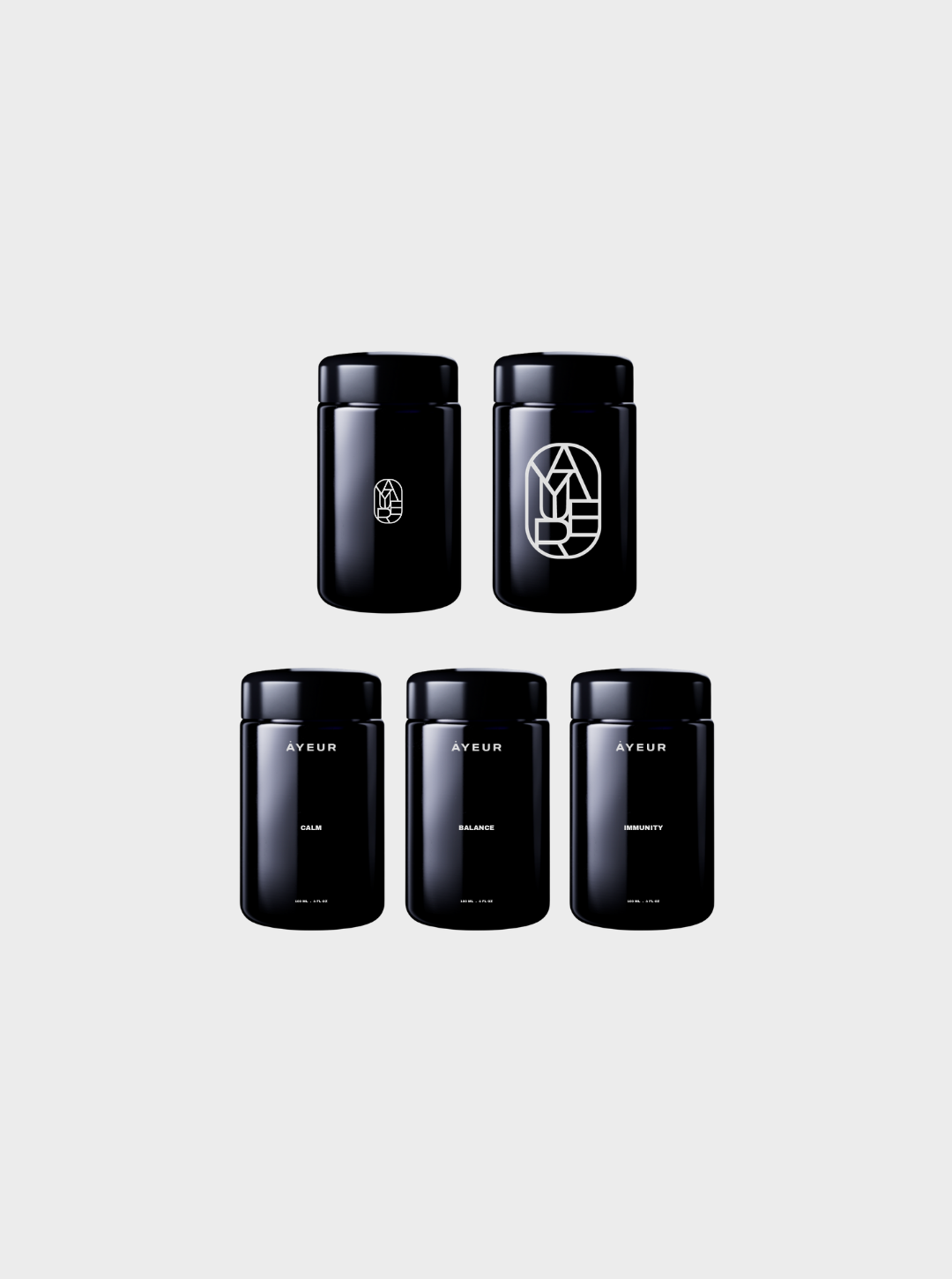 Set of five black bottles labeled with minimalist text, including 'Calm,' 'Balance,' and 'Immunity' from the brand 'Ayer' and a larger bottle with abstract line art on the label.