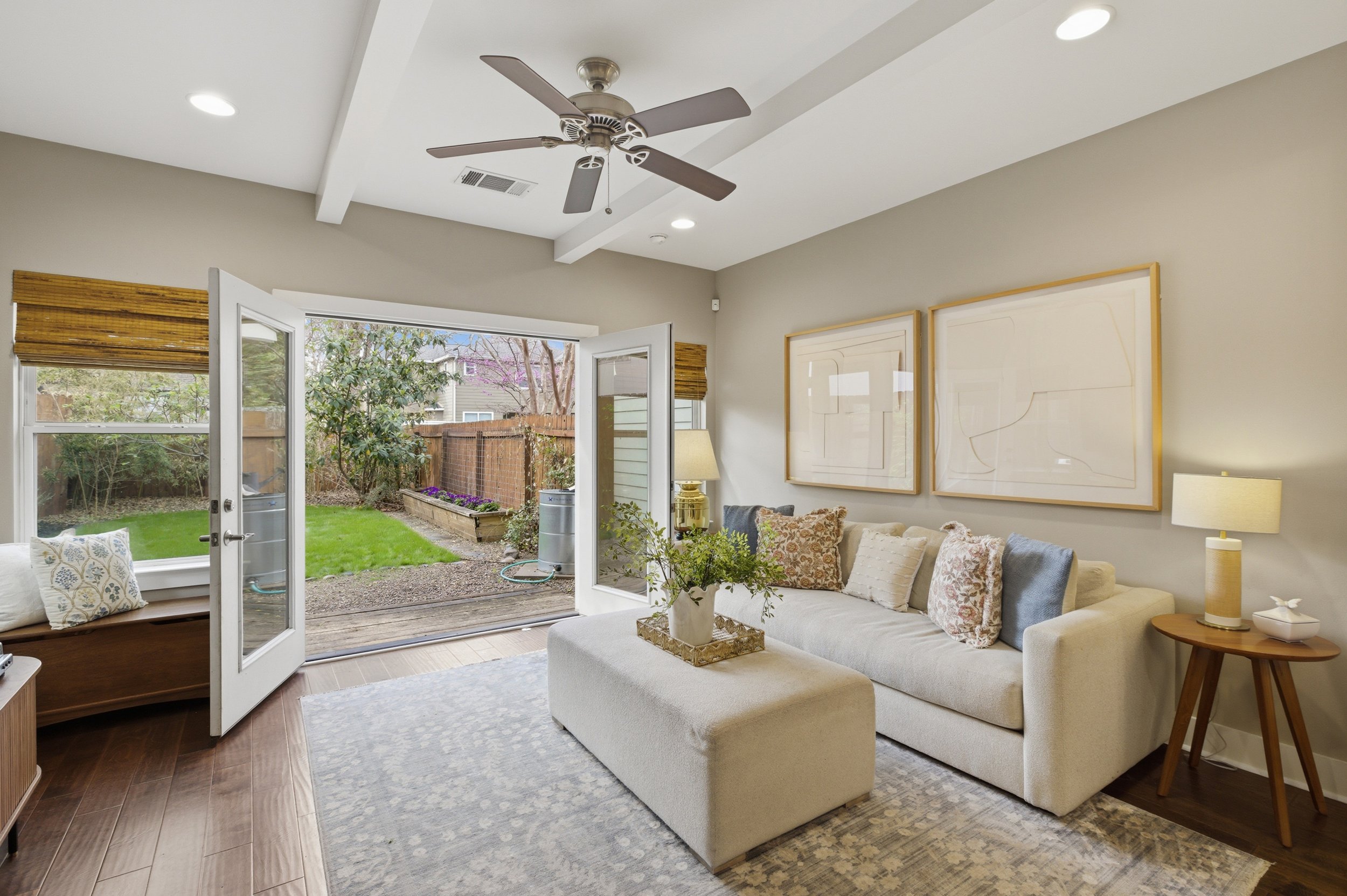 Bright open-concept living room in Brentwood Austin TX condo with large windows and French doors to backyard.
